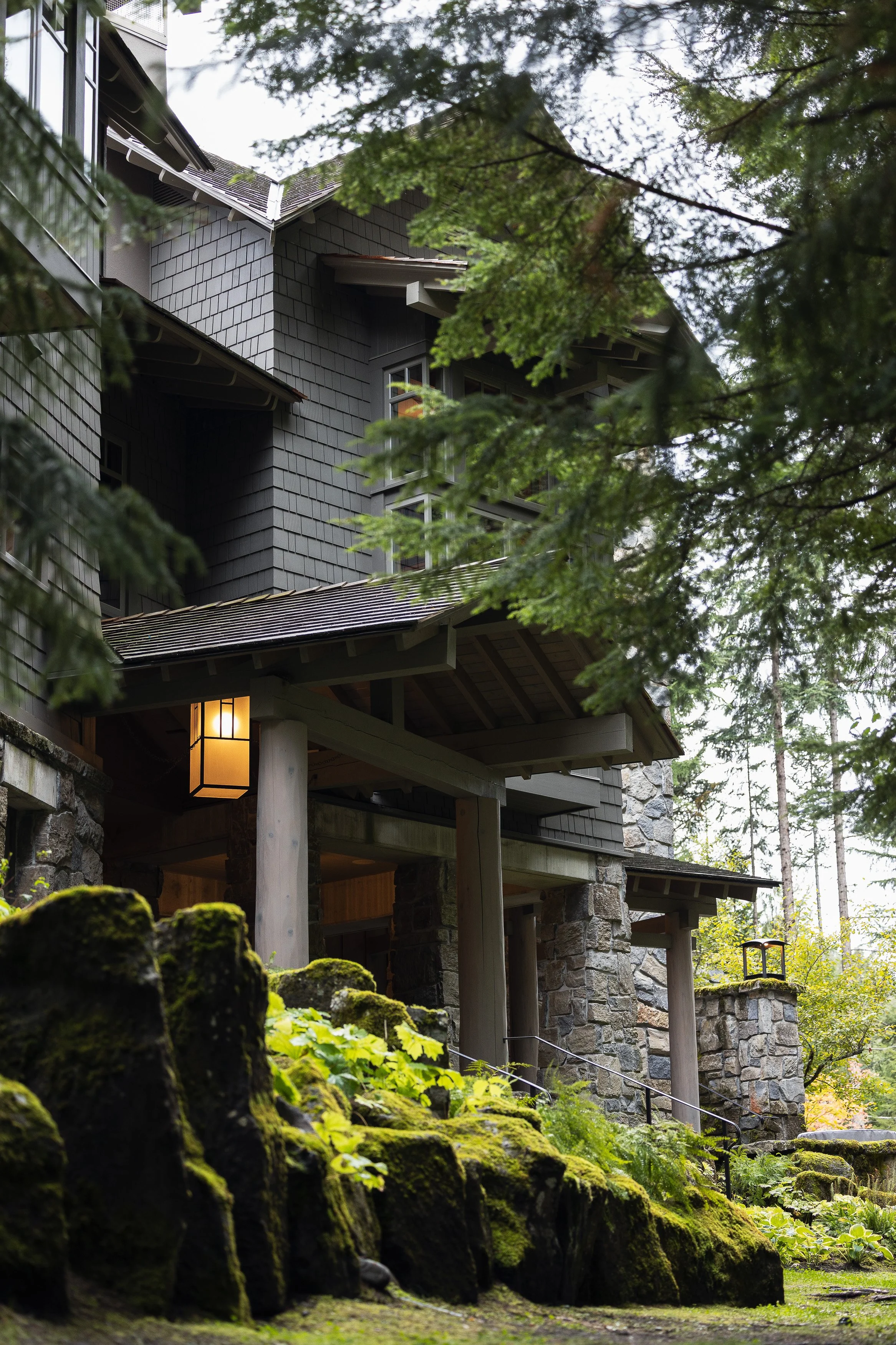 Exterior entry detail with mossy stone landscaping, timber structure, and lantern lighting at a Whistler home.