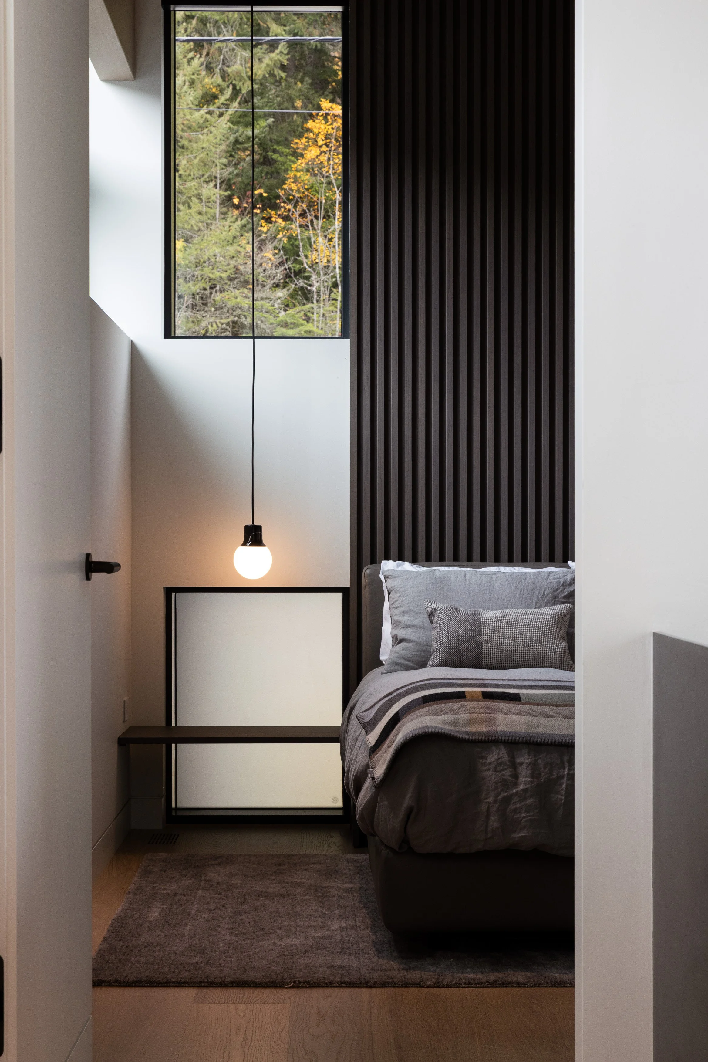 An intimate bedroom featuring vertical wood slat detailing, soft natural light, and carefully balanced proportions. Designed by Burgers Architecture and built by Durfeld Constructors, this Whistler interior reflects thoughtful residential architectur