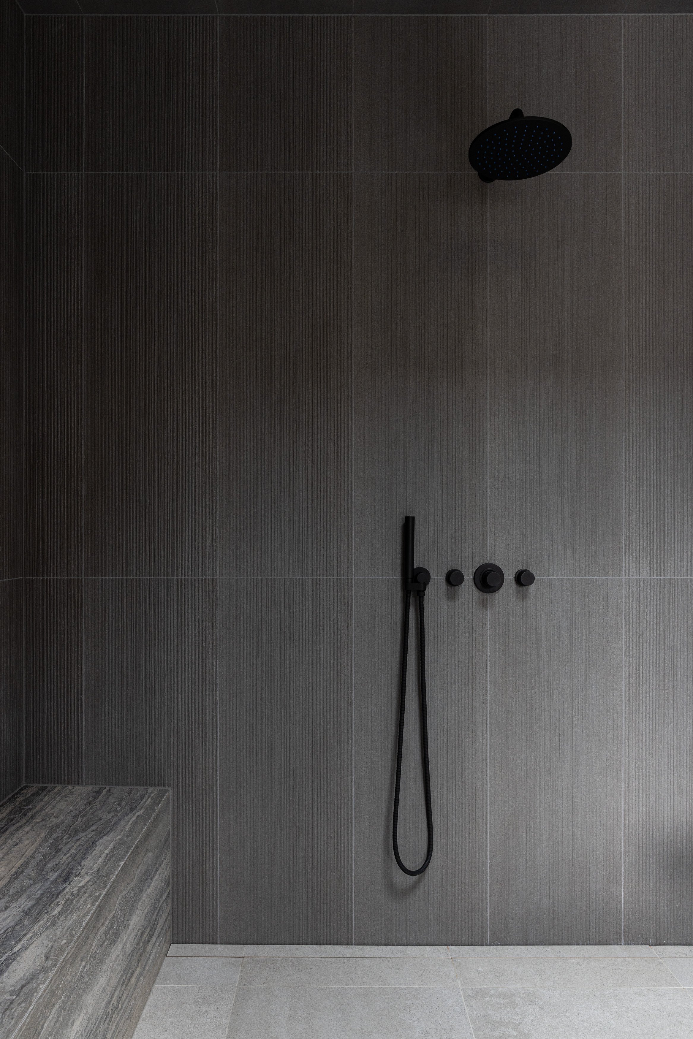 A minimalist walk-in shower with dark-toned tile, concealed fixtures, and a restrained material palette. Built by Durfeld Constructors and designed by Burgers Architecture, this space emphasizes clean lines and refined modern bathroom design.