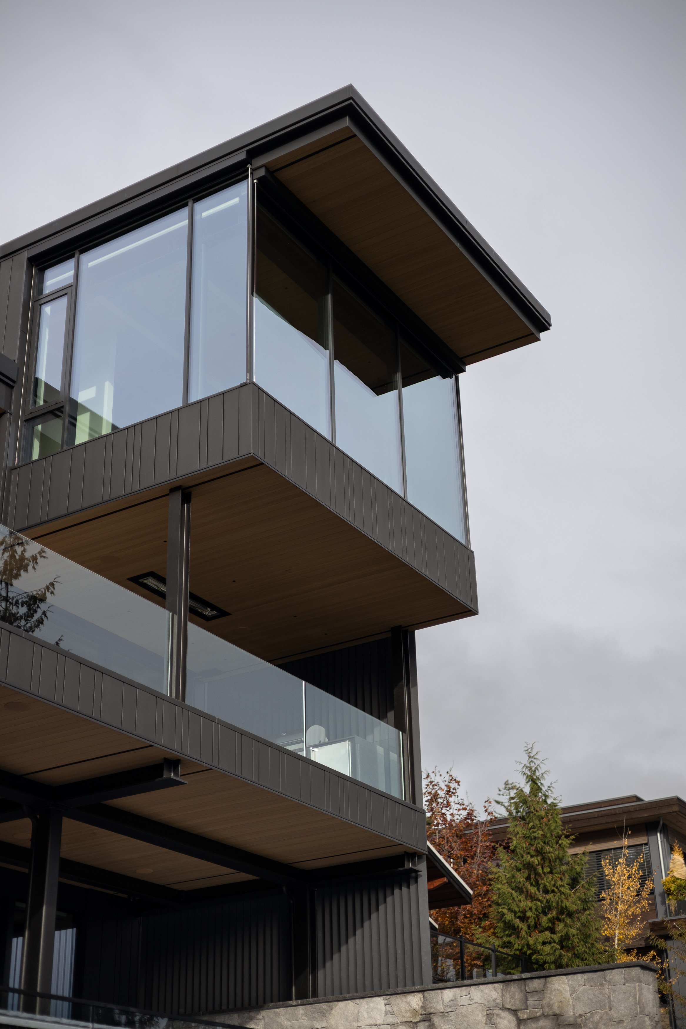 A detailed exterior perspective showcasing clean roof edges, expansive glazing, and dark cladding contrasted with warm wood soffits. This Whistler custom home reflects Durfeld Constructors’ precision construction and Burgers Architecture’s modern mou