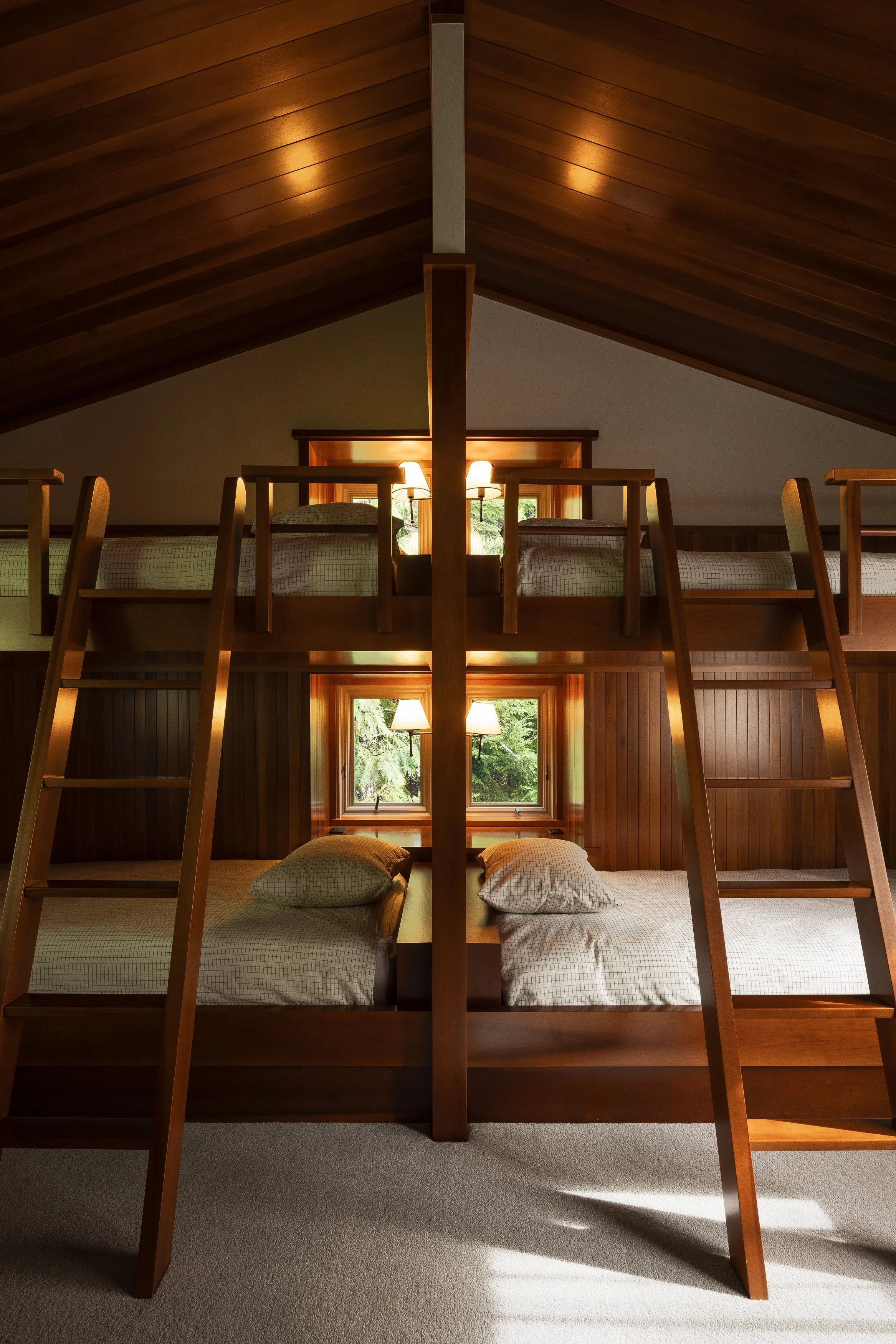 Cozy bunk room with custom wood bunks, ladders, and a pitched cedar ceiling in a Whistler mountain home.