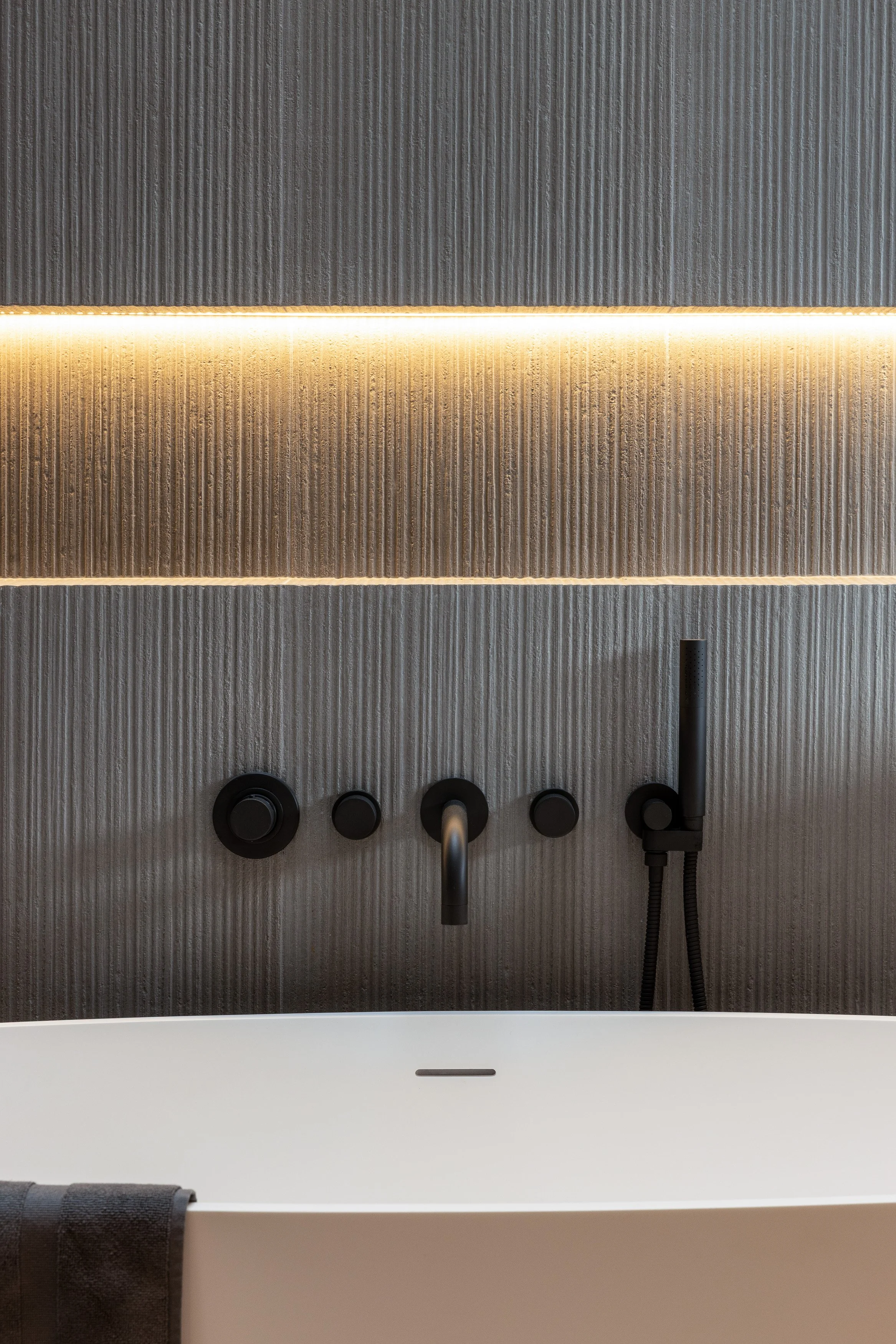 A close-up architectural detail highlighting textured wall surfaces and recessed linear lighting within the bathroom. This Whistler custom home showcases Durfeld Constructors’ craftsmanship and Burgers Architecture’s attention to subtle, high-end det