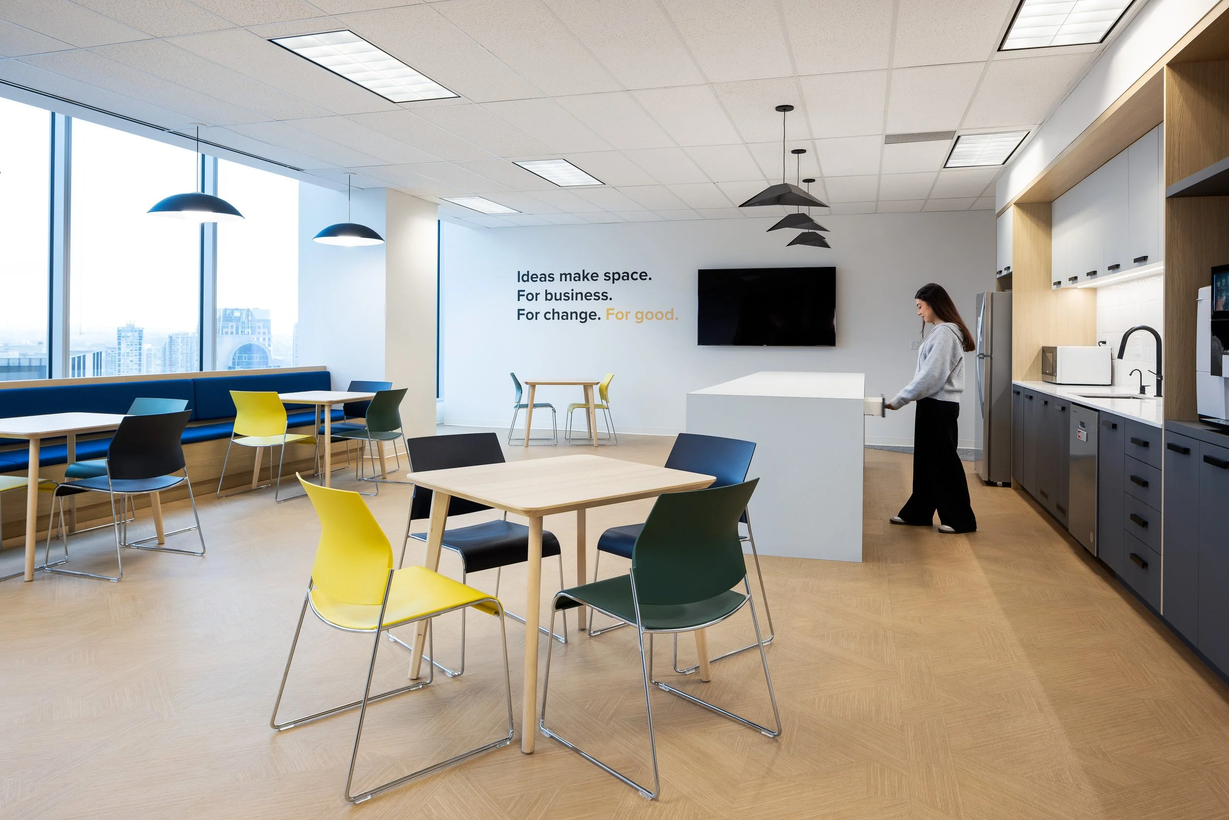 Staff kitchen and informal meeting area at the Mott MacDonald Vancouver office, featuring banquette seating, café tables, and a central island.
