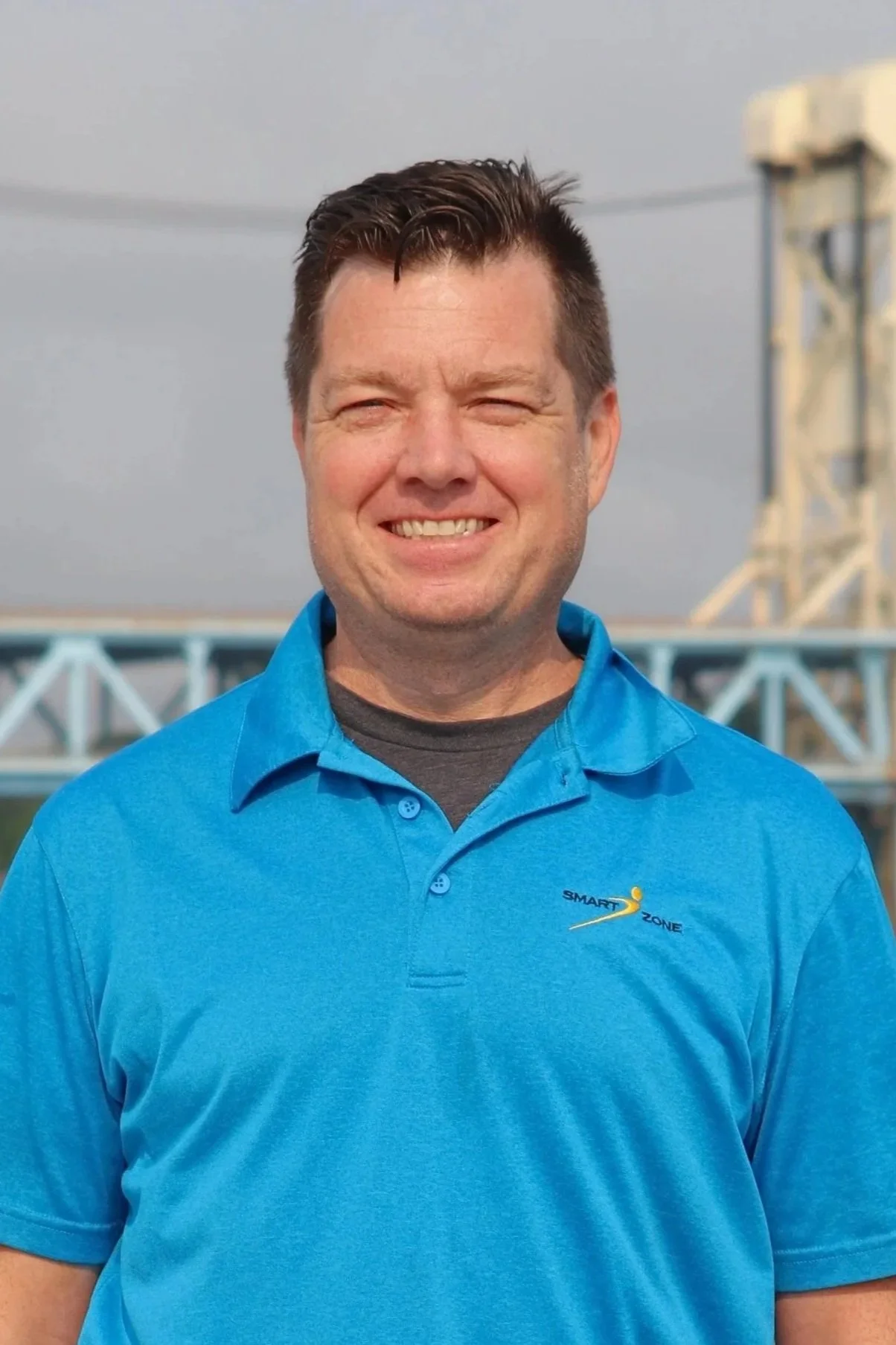Smiling person wearing a black "Smart Zone" polo shirt