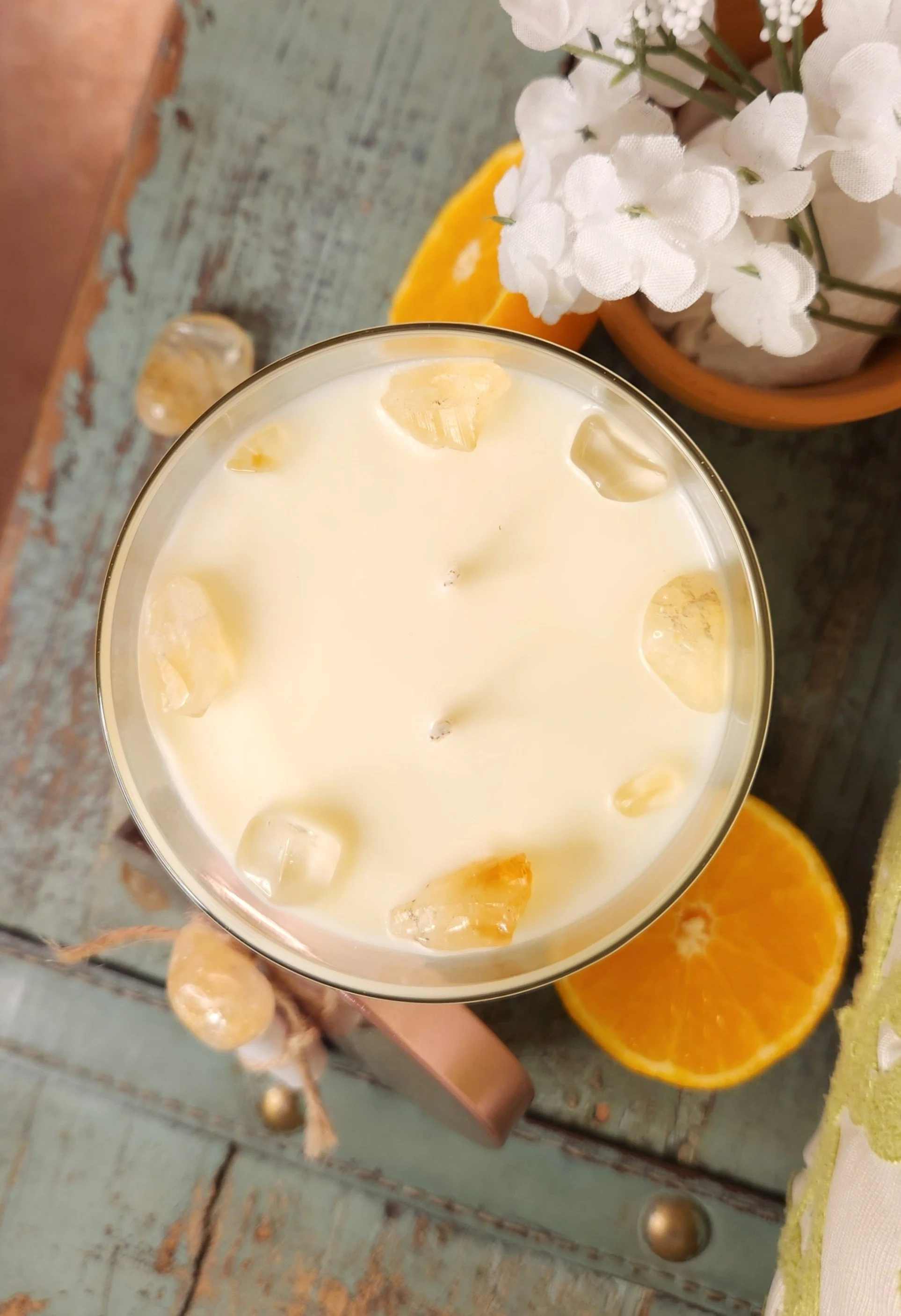 Beautiful two wick soy candle sitting on a table near a juicy sliced orange to show the scent of the Healing Light Soy Candle called Summer Mornings Citrine