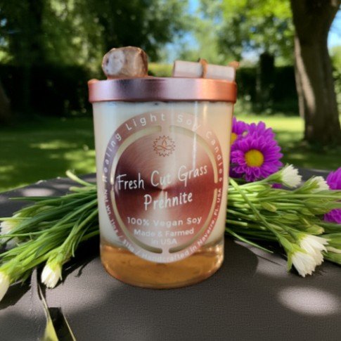 Fresh Cut Grass 11oz Cap on on a wooden table with flowers around it with lawn.jpg