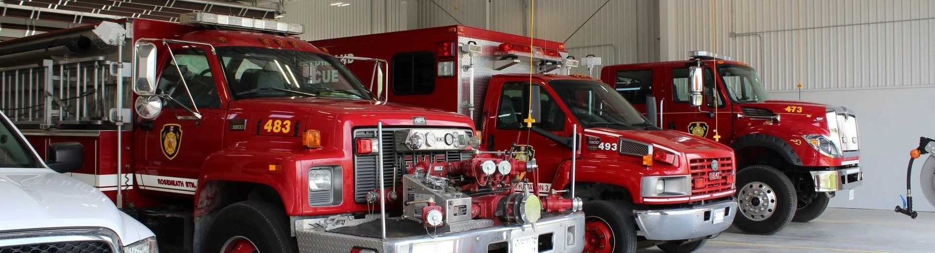 Three red fire trucks parked inside a fire station garage.