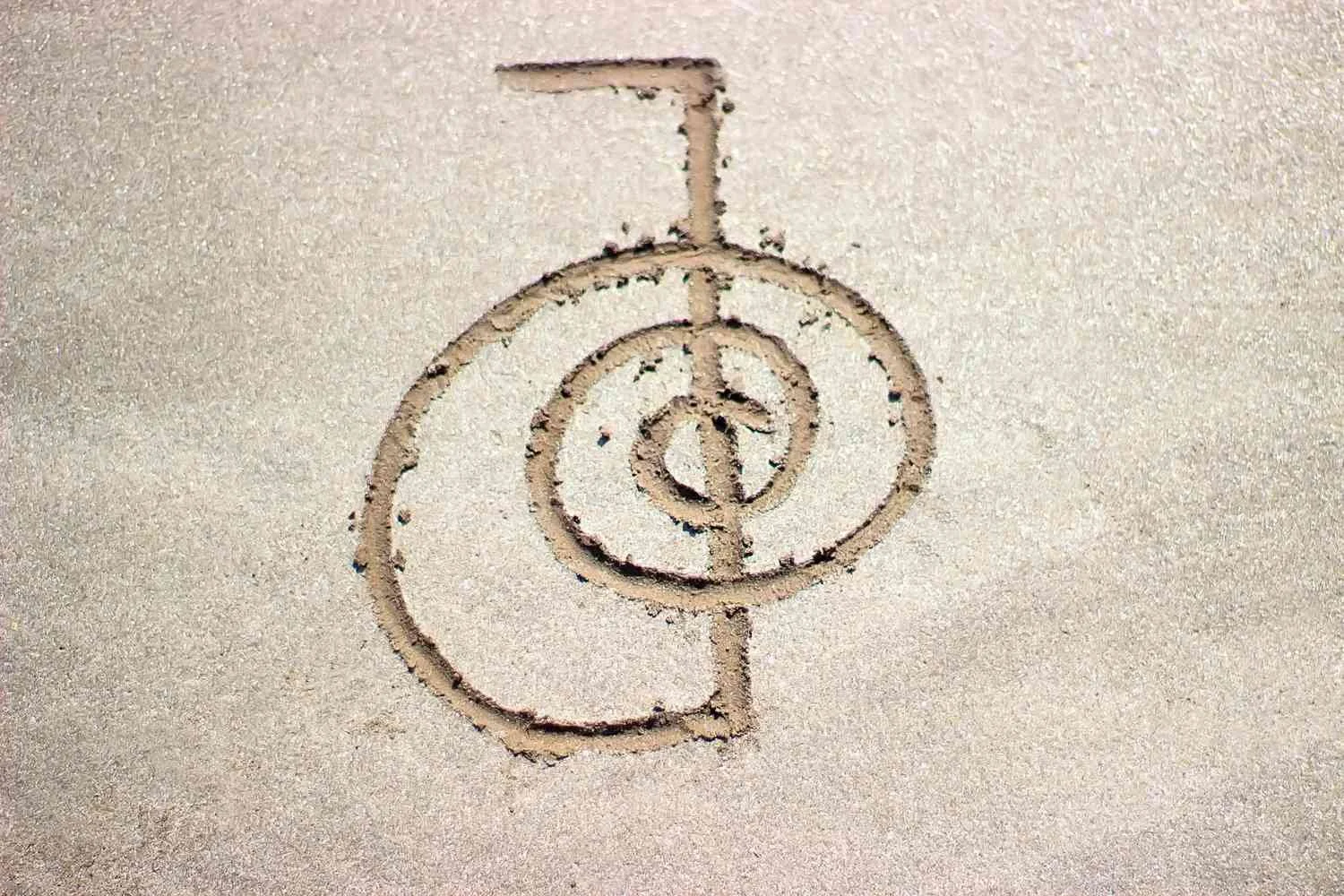 A dollar sign with a line through it drawn in the sand.