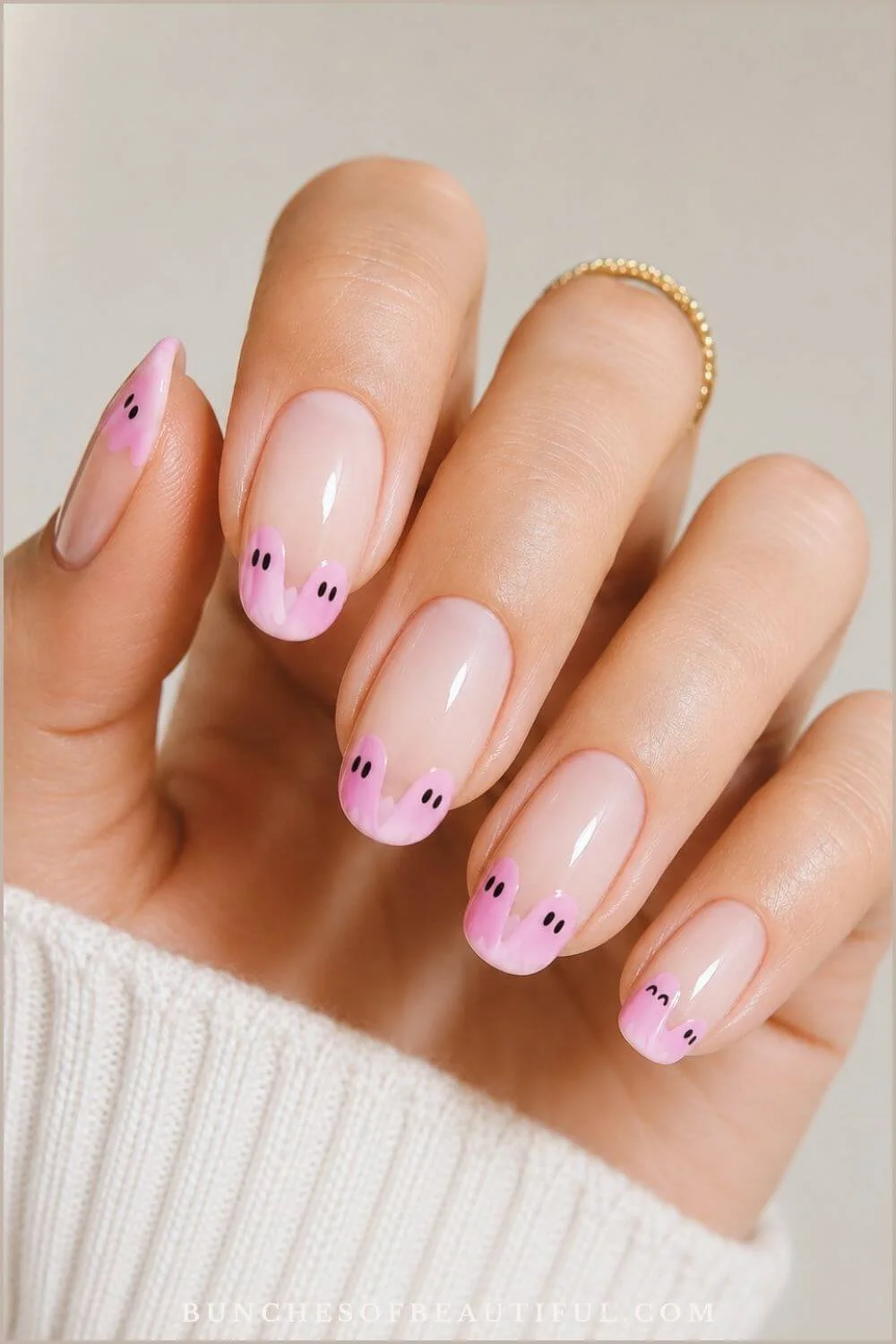 Sheer pink almond nails with playful pastel-pink ghost French tips and tiny black faces.