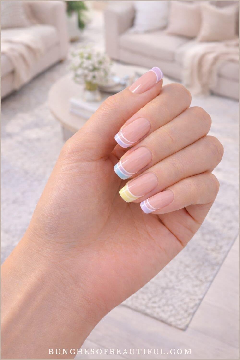 Spring pastel French tip nails with soft purple, blue, and yellow tips and thin double line accents on long square nails.