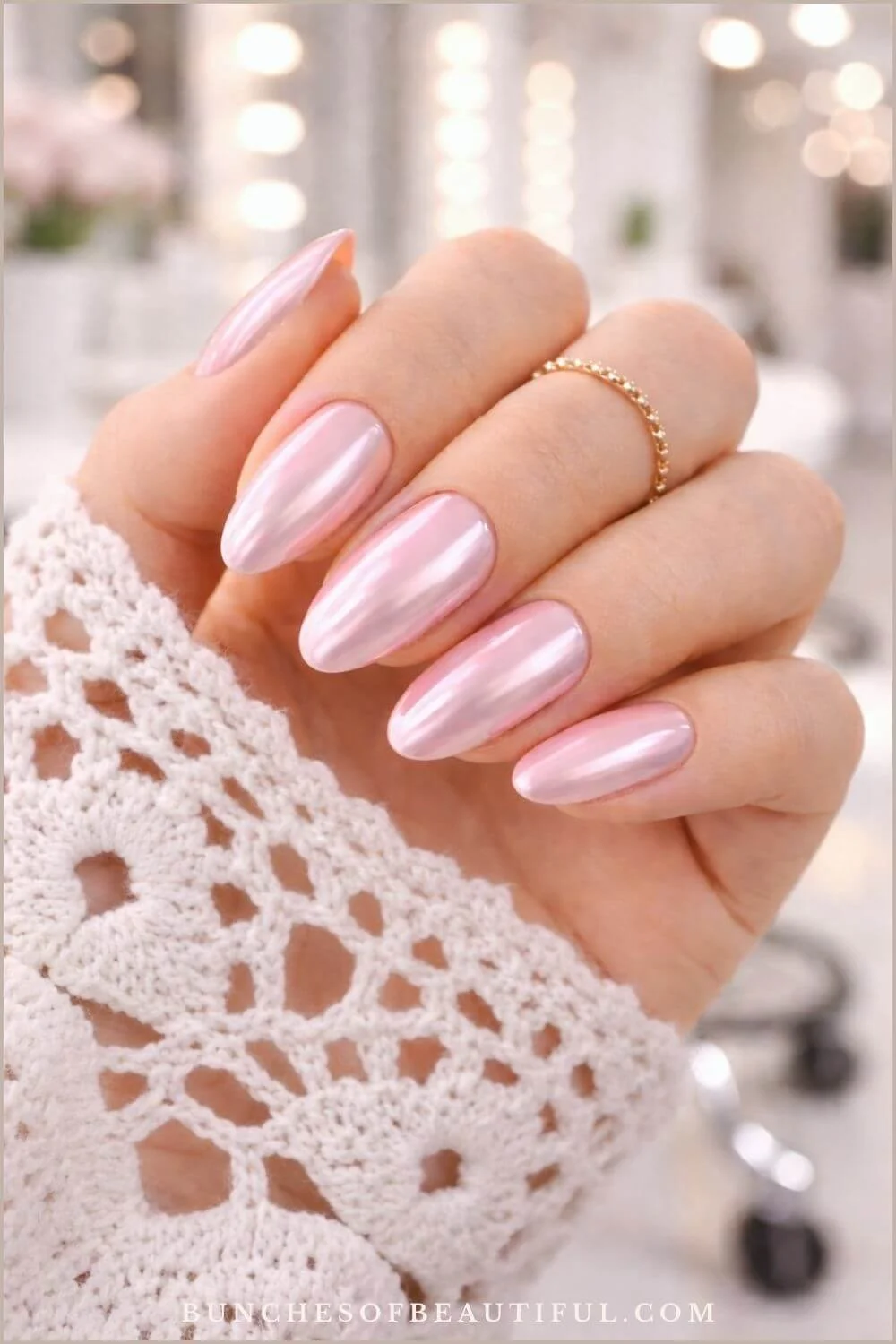 Pink chrome spring nails on long almond shaped nails with glossy reflective finish photographed with a lace sleeve.