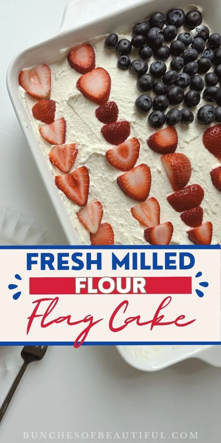 Fresh milled flour flag cake topped with vanilla whipped cream, blueberries, and sliced strawberries, with text overlay that says Fresh Milled Flour Flag Cake.