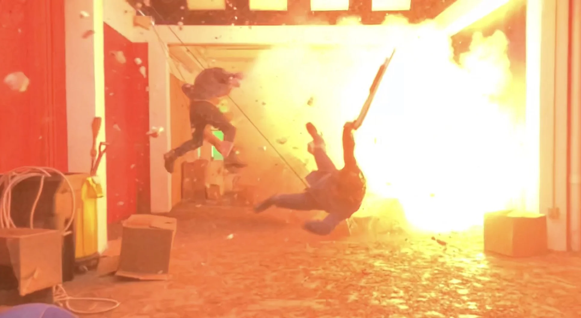 Two people are being propelled into the air by a large explosion in a hallway.