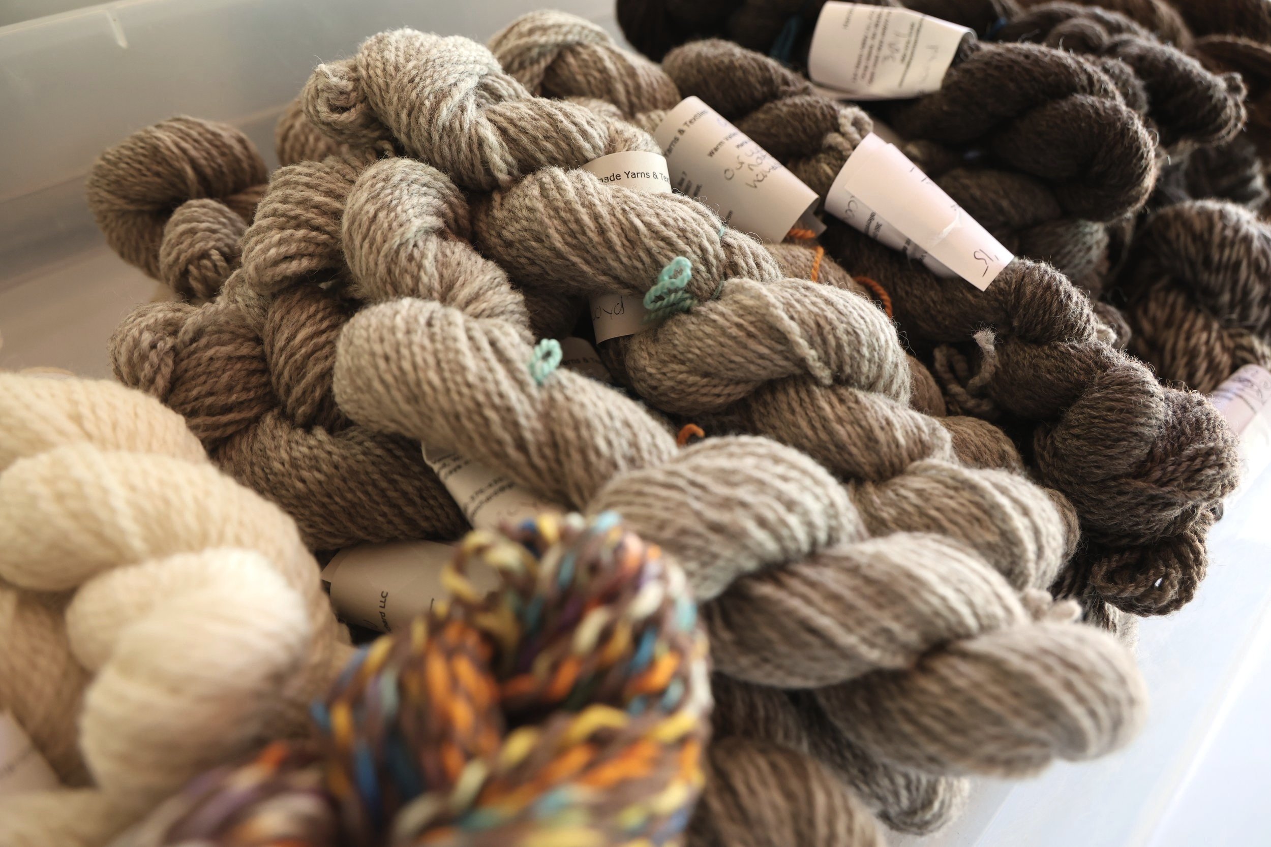brown, white, and tan yarn in a bin