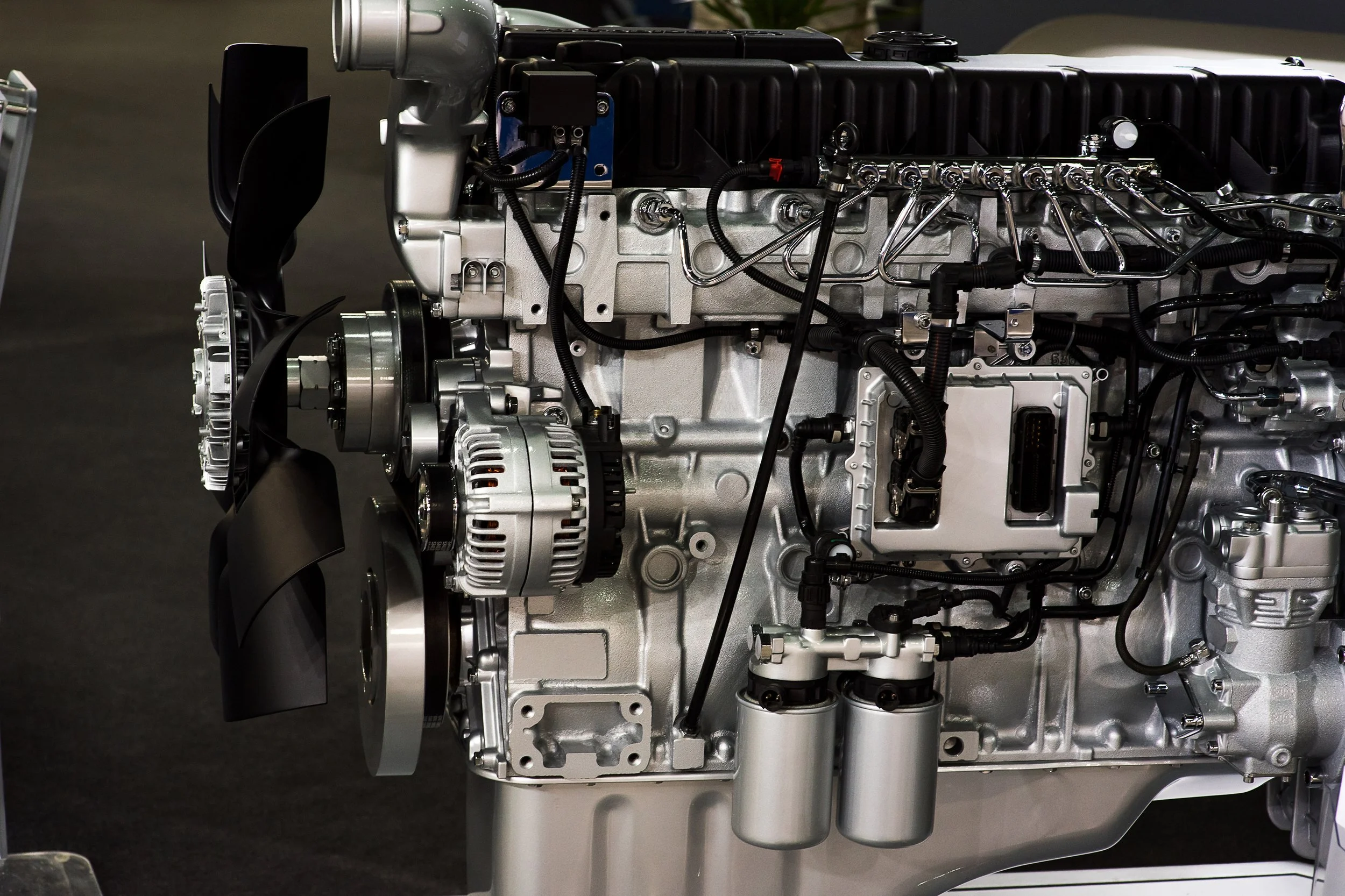 Close-up of a modern car engine, showing details of the belts, pulleys, electrical connections, and components.