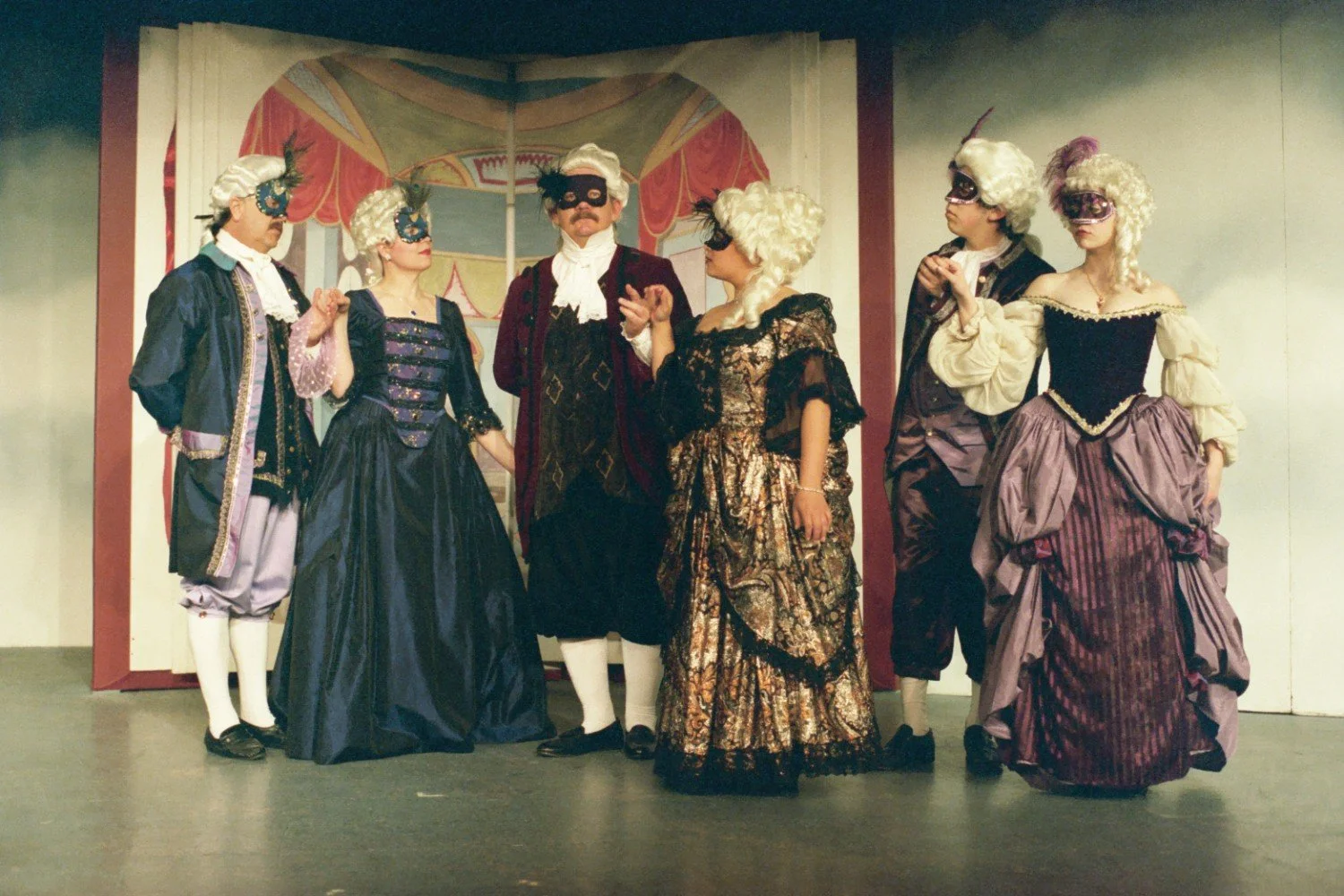 People in baroque costumes with masks standing on stage