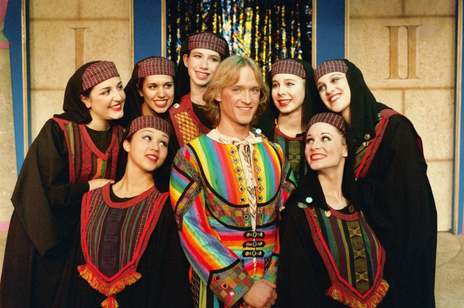 Group photo from a theatrical performance with actors in colorful costumes.