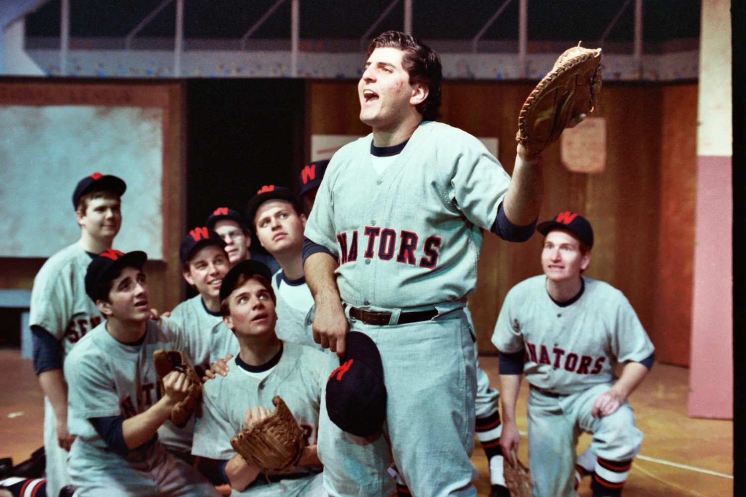Group of men in vintage baseball uniforms engaging in a theatrical performance.