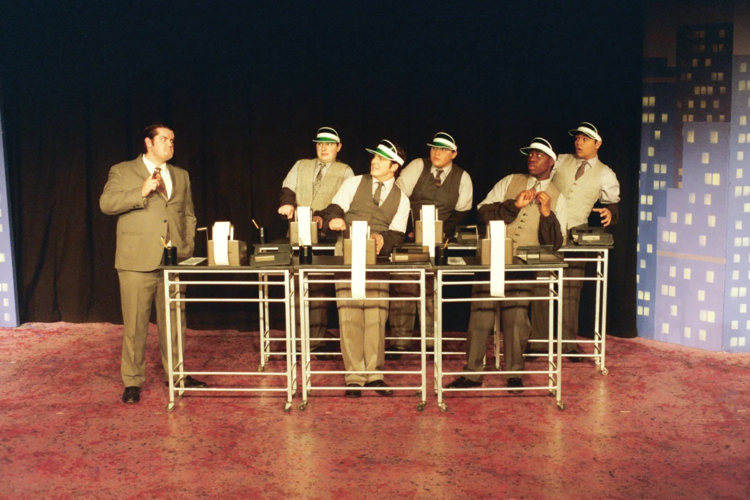 Group of performers on stage in business attire with vintage adding machines