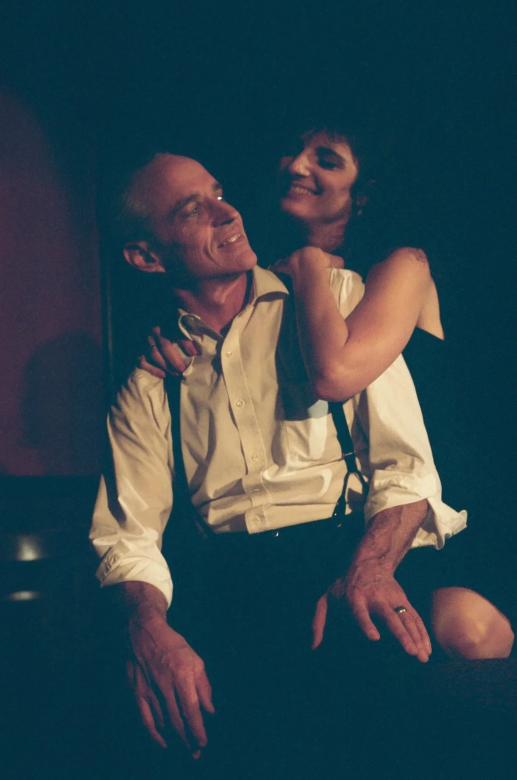 Man and woman in warm lighting, the woman playfully hugging the man.