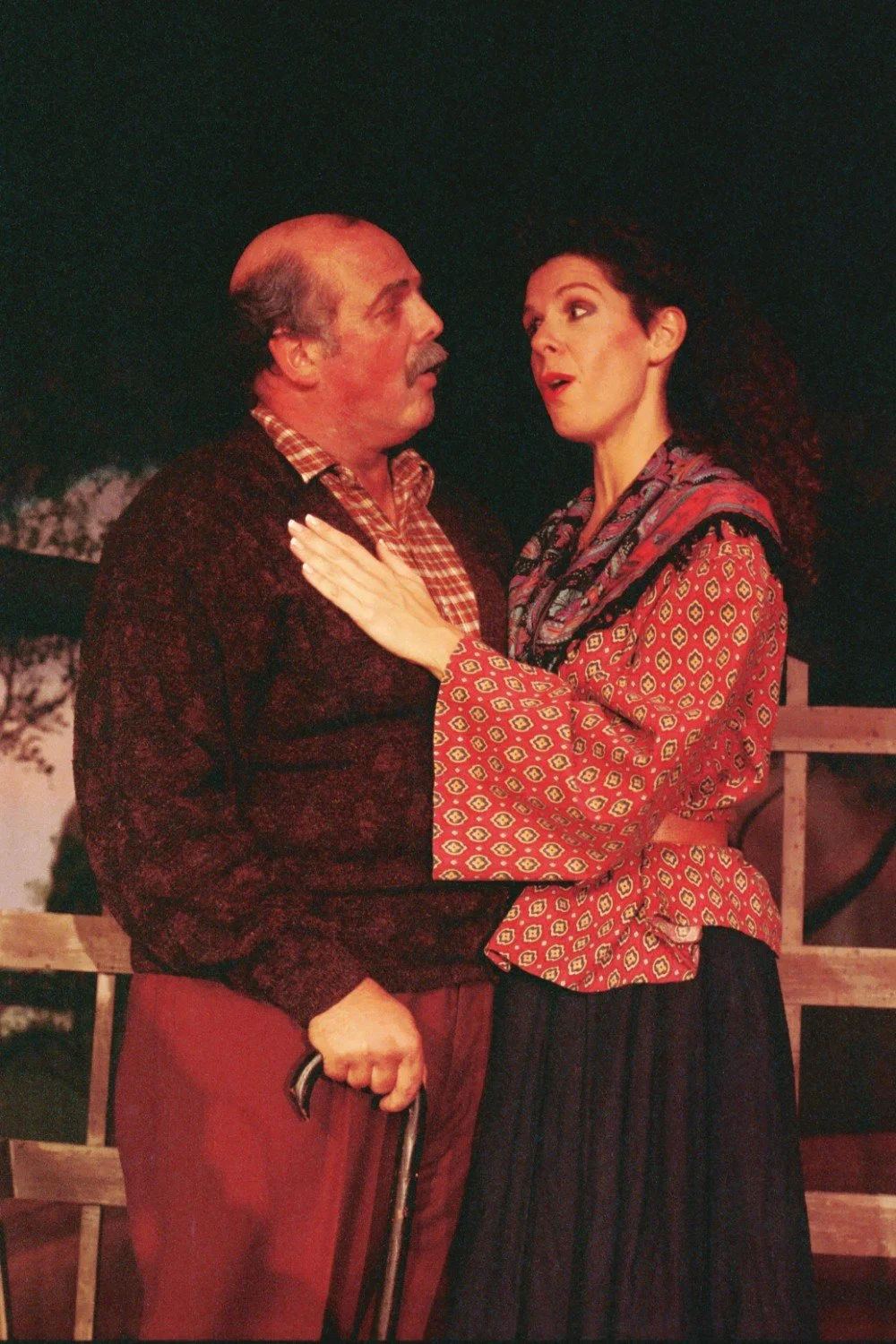 Two people performing on stage, one holding a cane, in a dramatic scene.