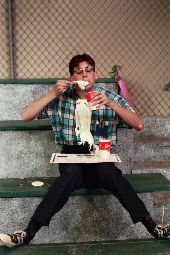 Man eating melted ice cream at a stadium.