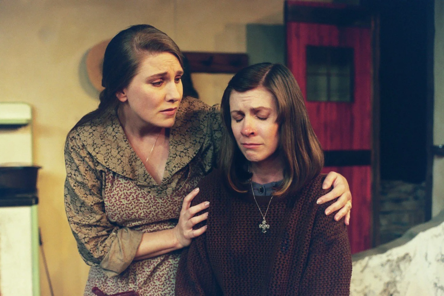 Two women in a dramatic scene; one is comforting the other who appears upset.