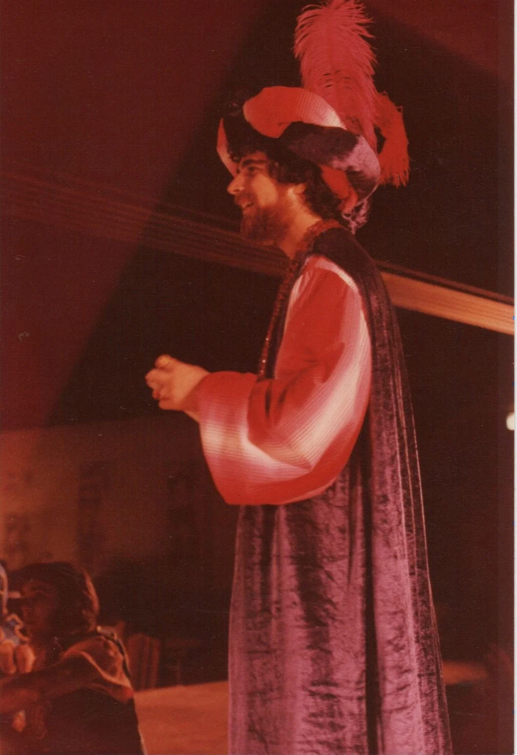 Person in historical costume with a feathered hat on stage.