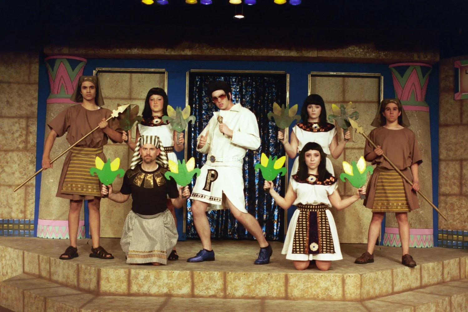 Group of people in Egyptian-themed costumes on stage with props