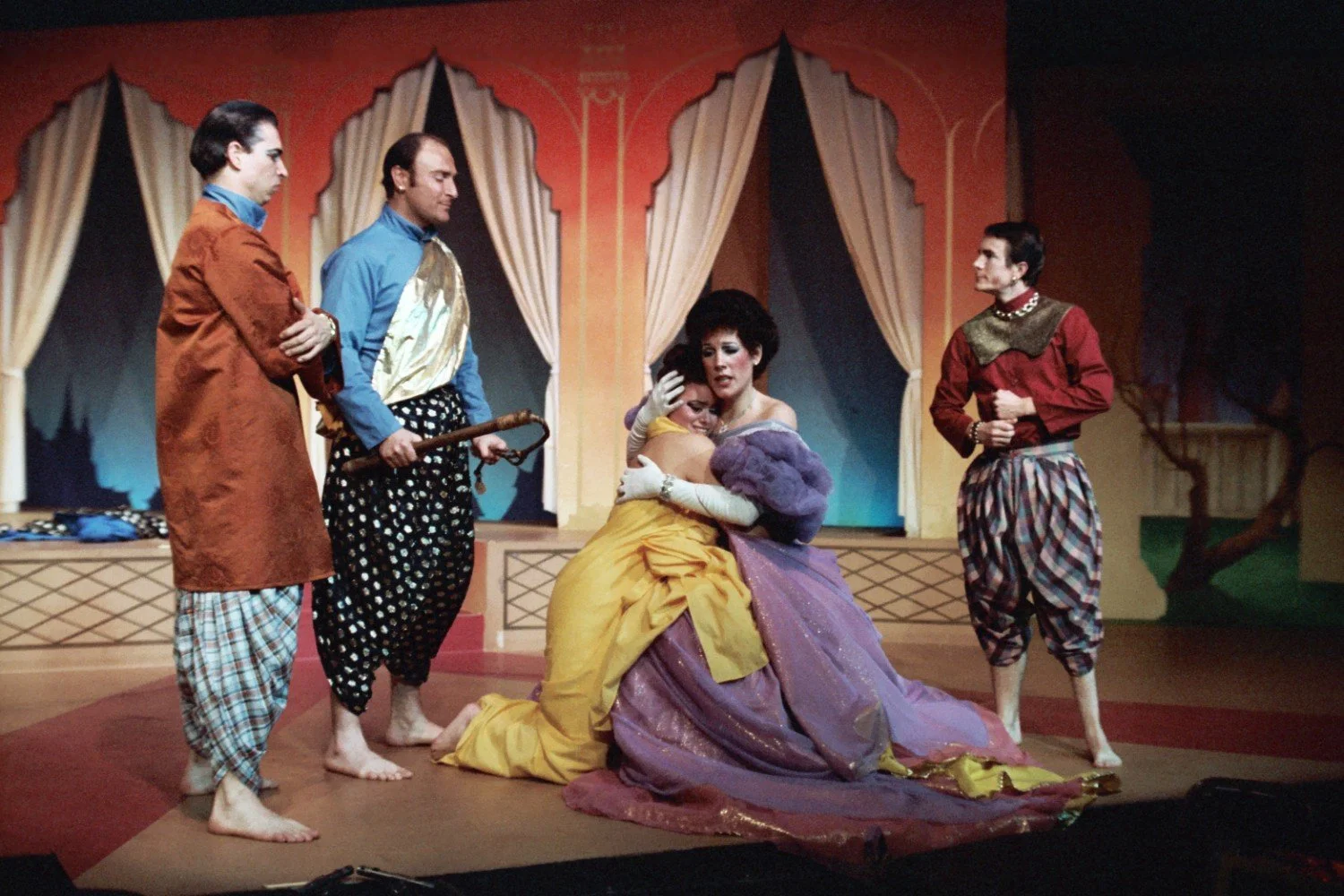 Theatrical performance with five actors in colorful costumes on stage.