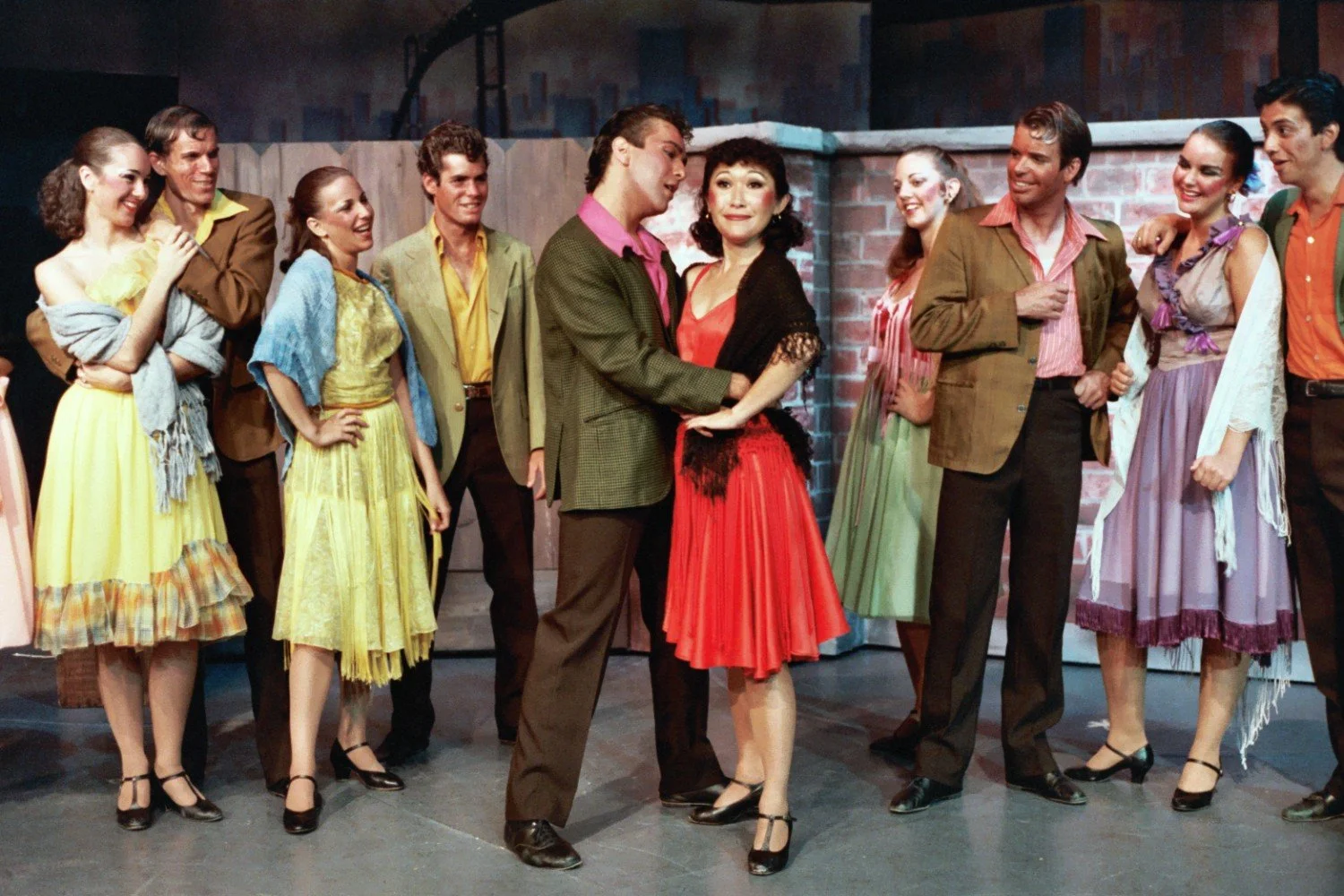 Group of performers on stage in vibrant costumes during a theater production.