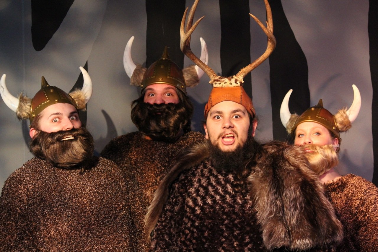 Four people dressed as Vikings with beards and horned helmets.