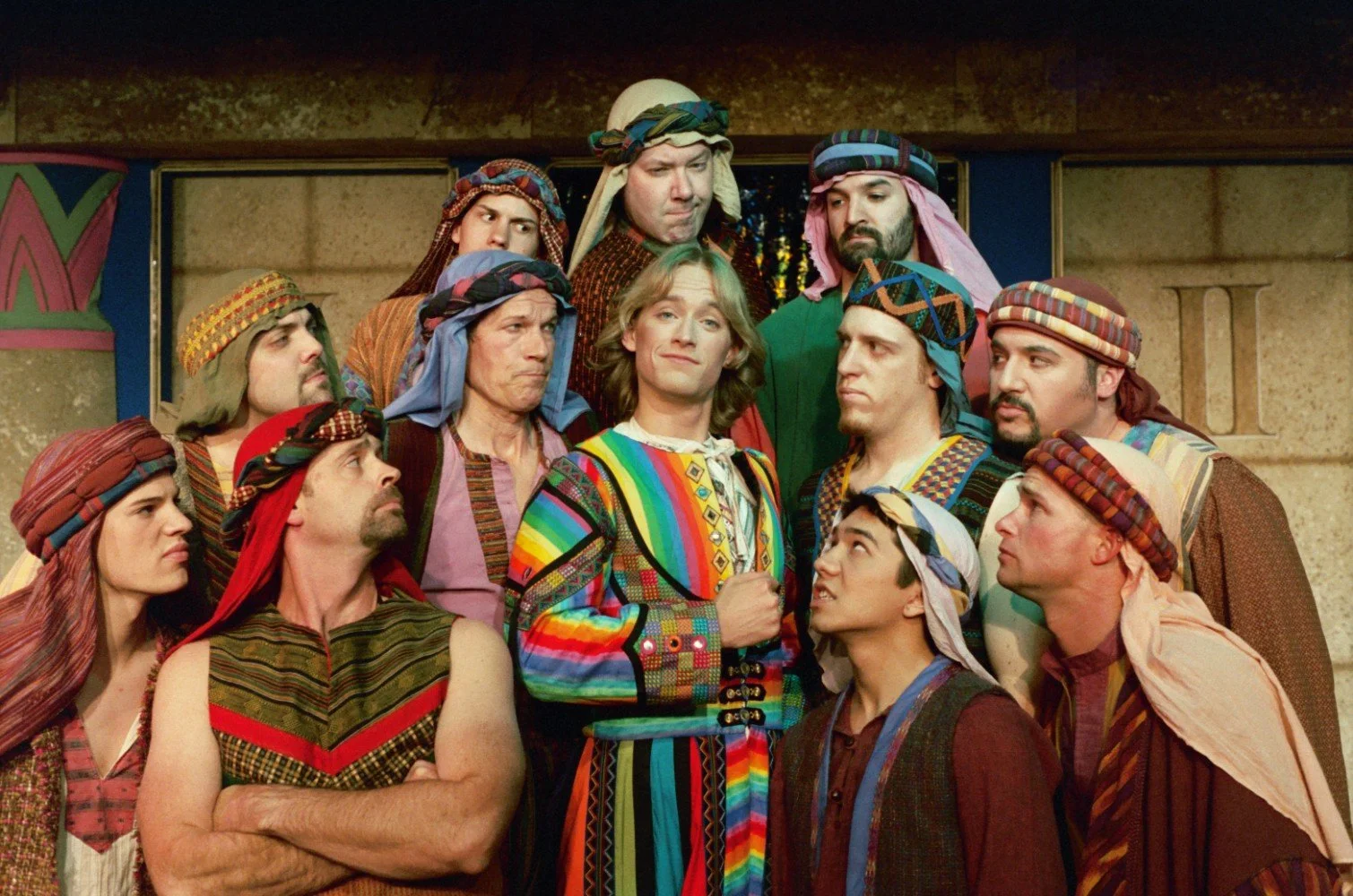 Group of actors in colorful, biblical-style costumes from a stage production.