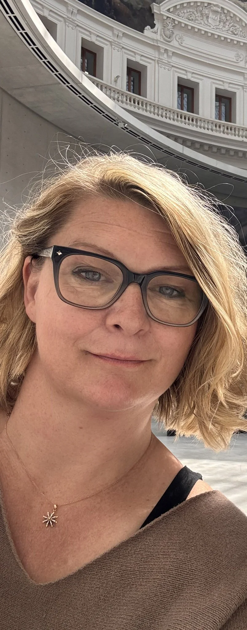 A woman wearing glasses standing in Paris' La Bourse de Commerce redesigned by Tadao Ando.