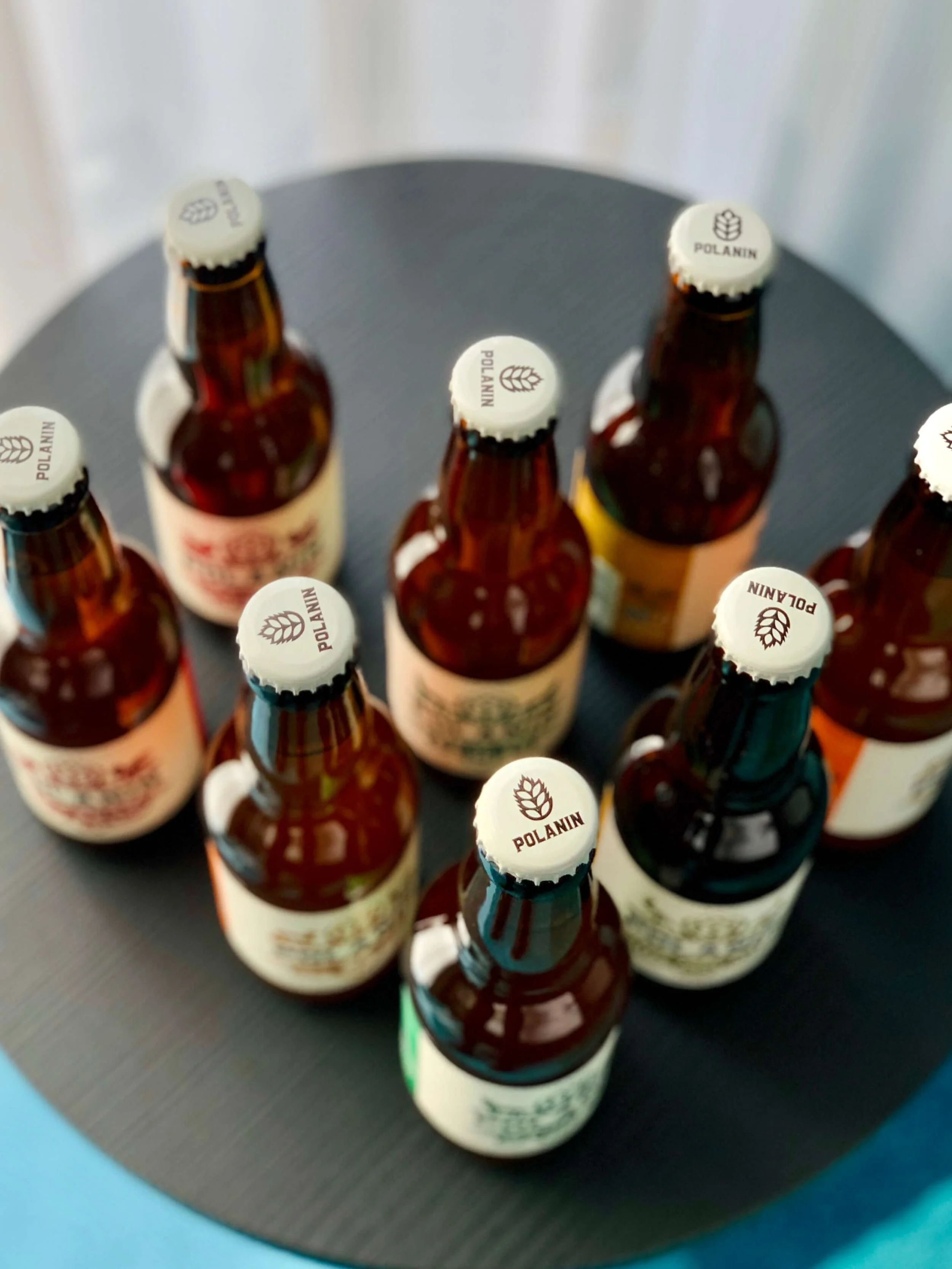 Multiple small glass bottles with white caps labeled "Polanin" on a round black surface.