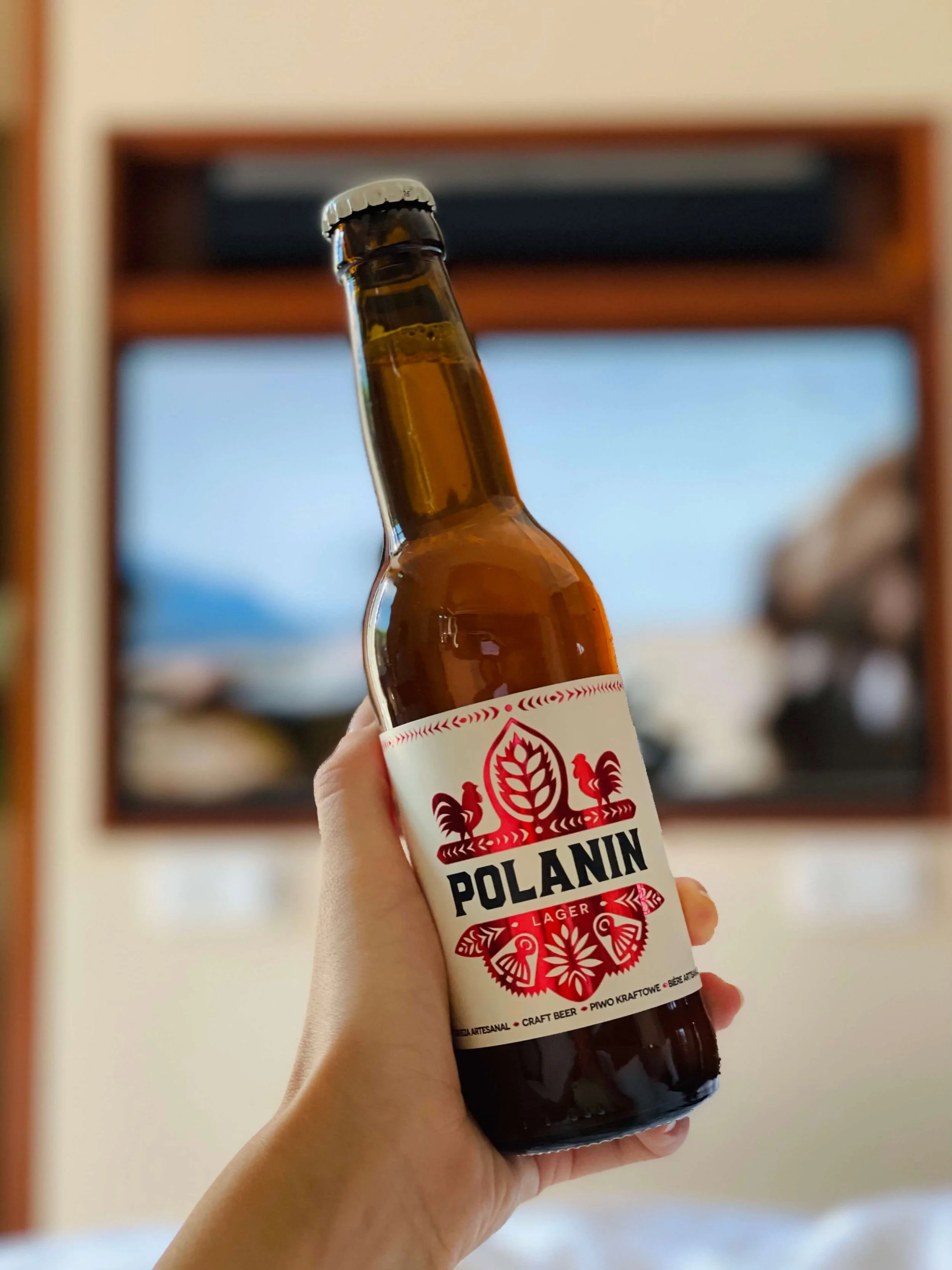 Polanin Lager craft beer with a white label and red designs, bottle cap on.