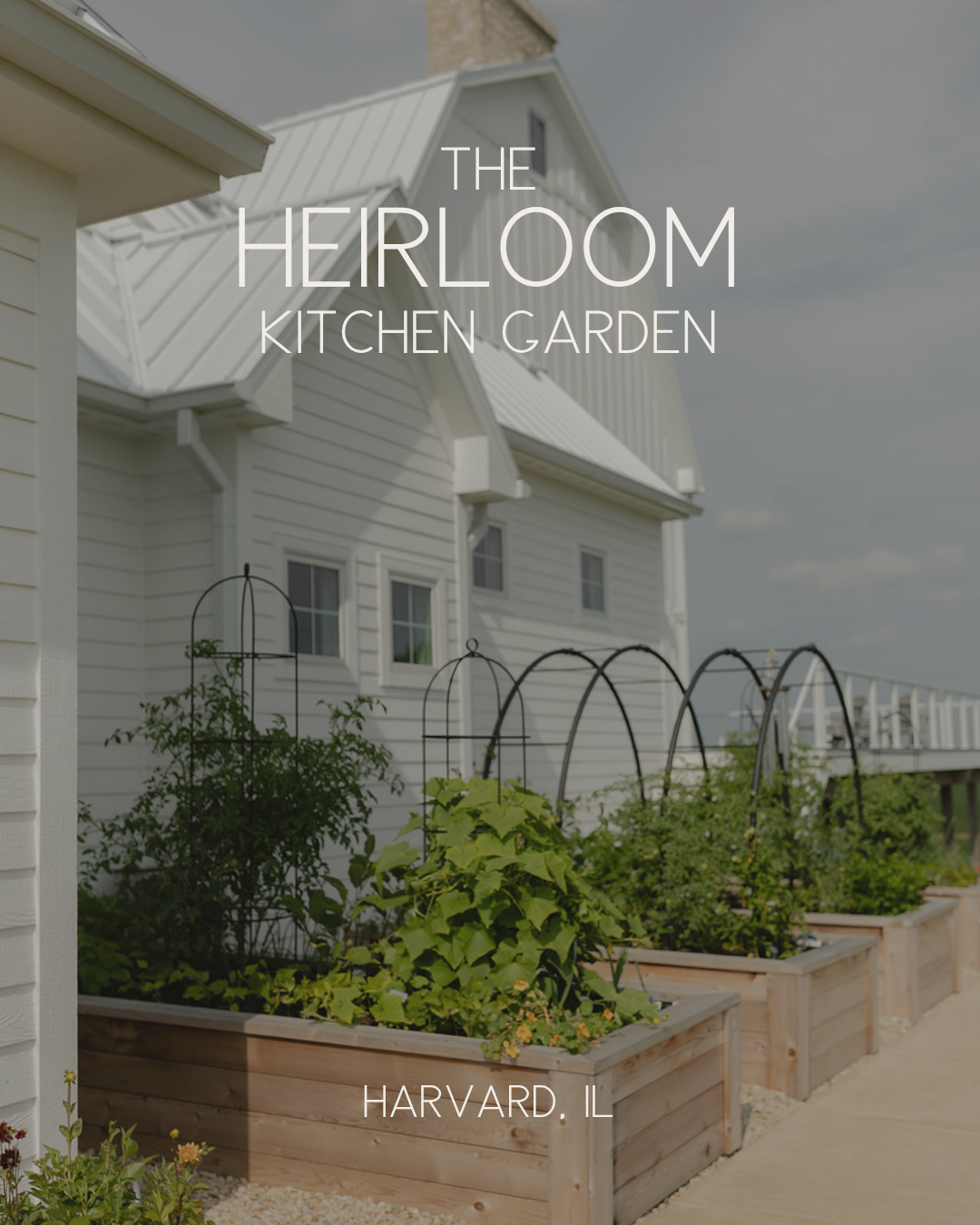 The Heirloom Kitchen Garden with cedar raised beds and custom black trellises beside a restored family farmhouse in Harvard, Illinois.