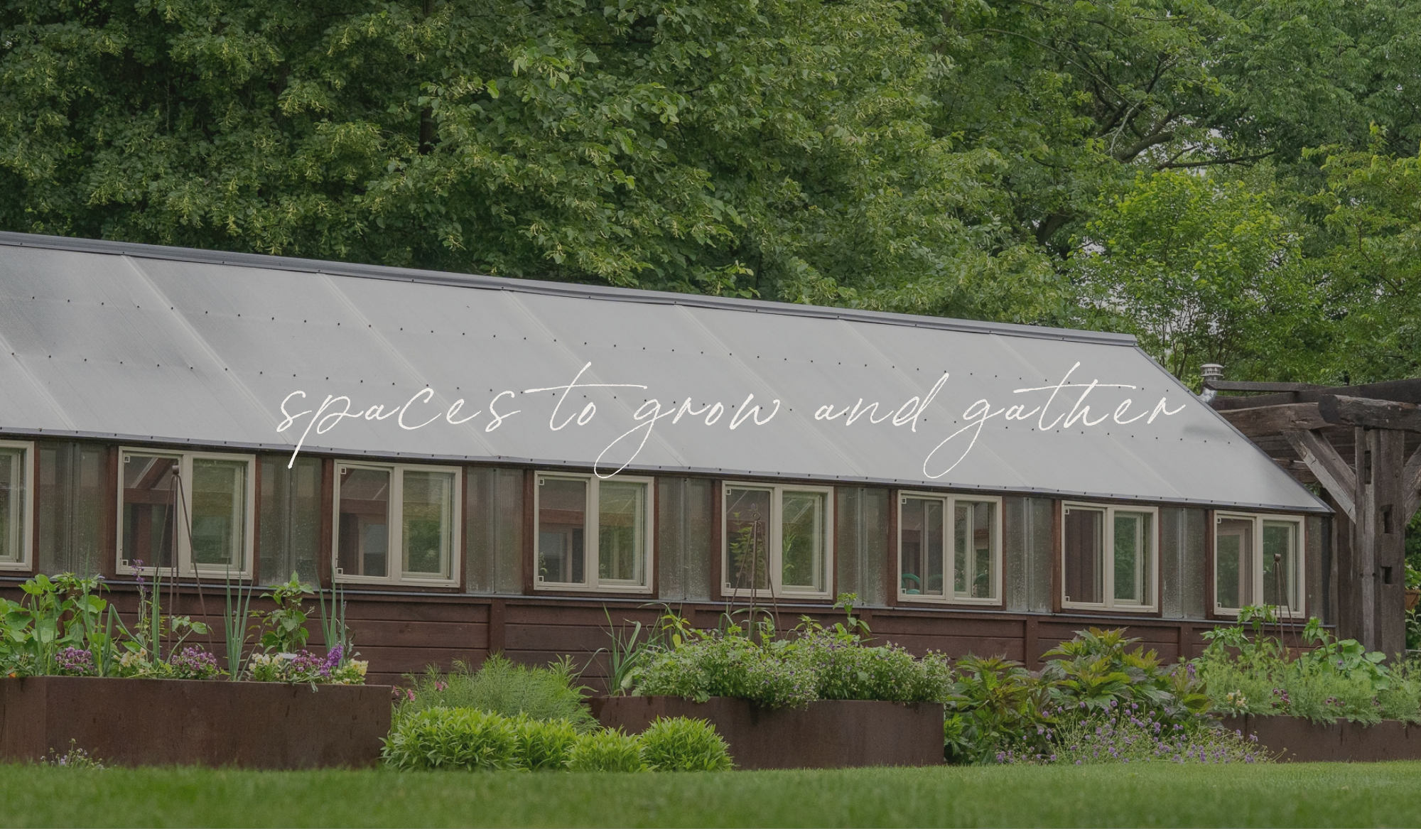 Yoderbilt greenhouse at The Edible Acre with corten steel planters filled with herbs and flowers, overlaid with the words "spaces to grow and gather."