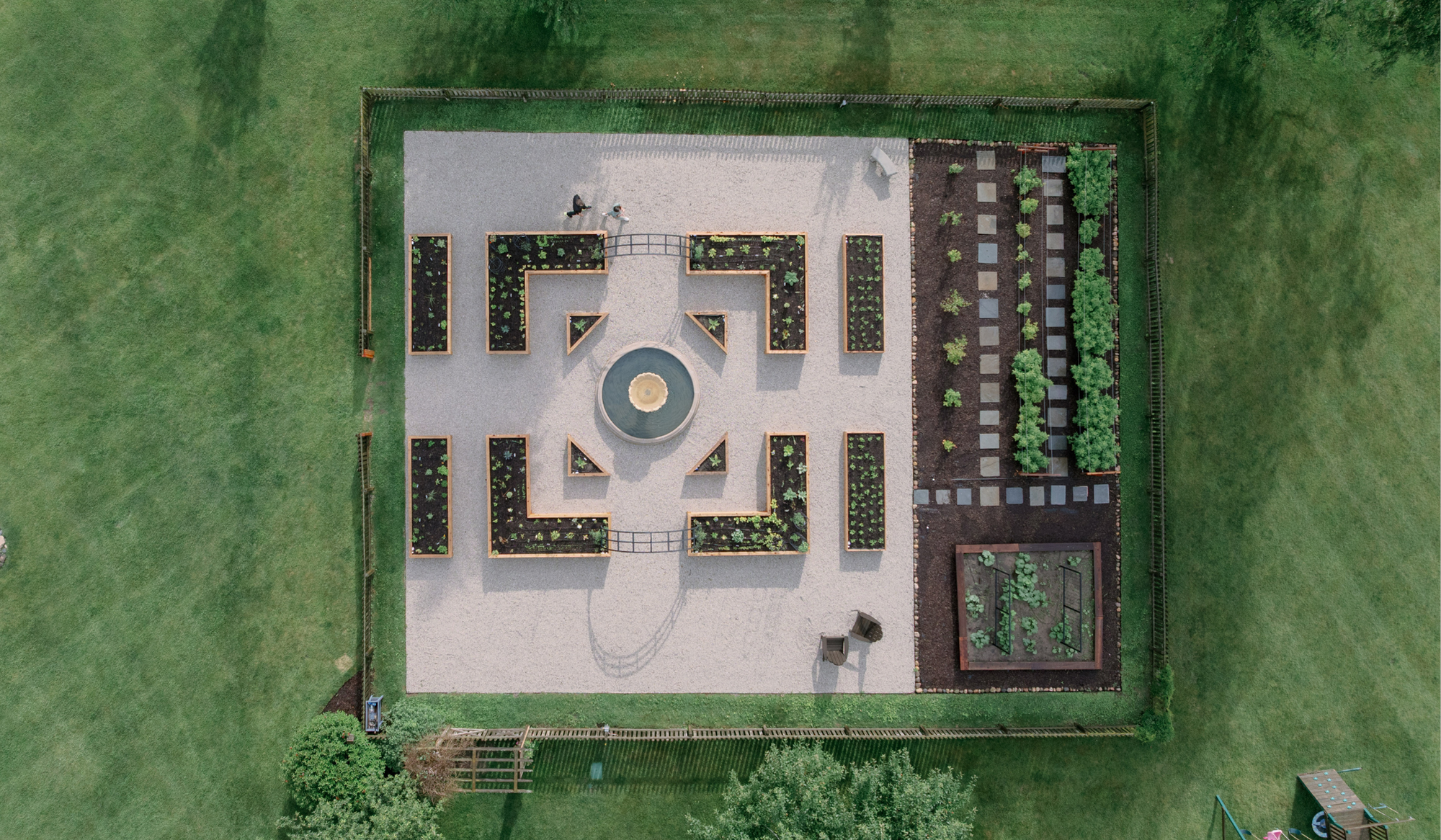 Aerial view of the LaRocque Farms kitchen garden in Walworth, Wisconsin, showing the symmetrical potager layout, central fountain, cedar raised beds, and arch trellises.