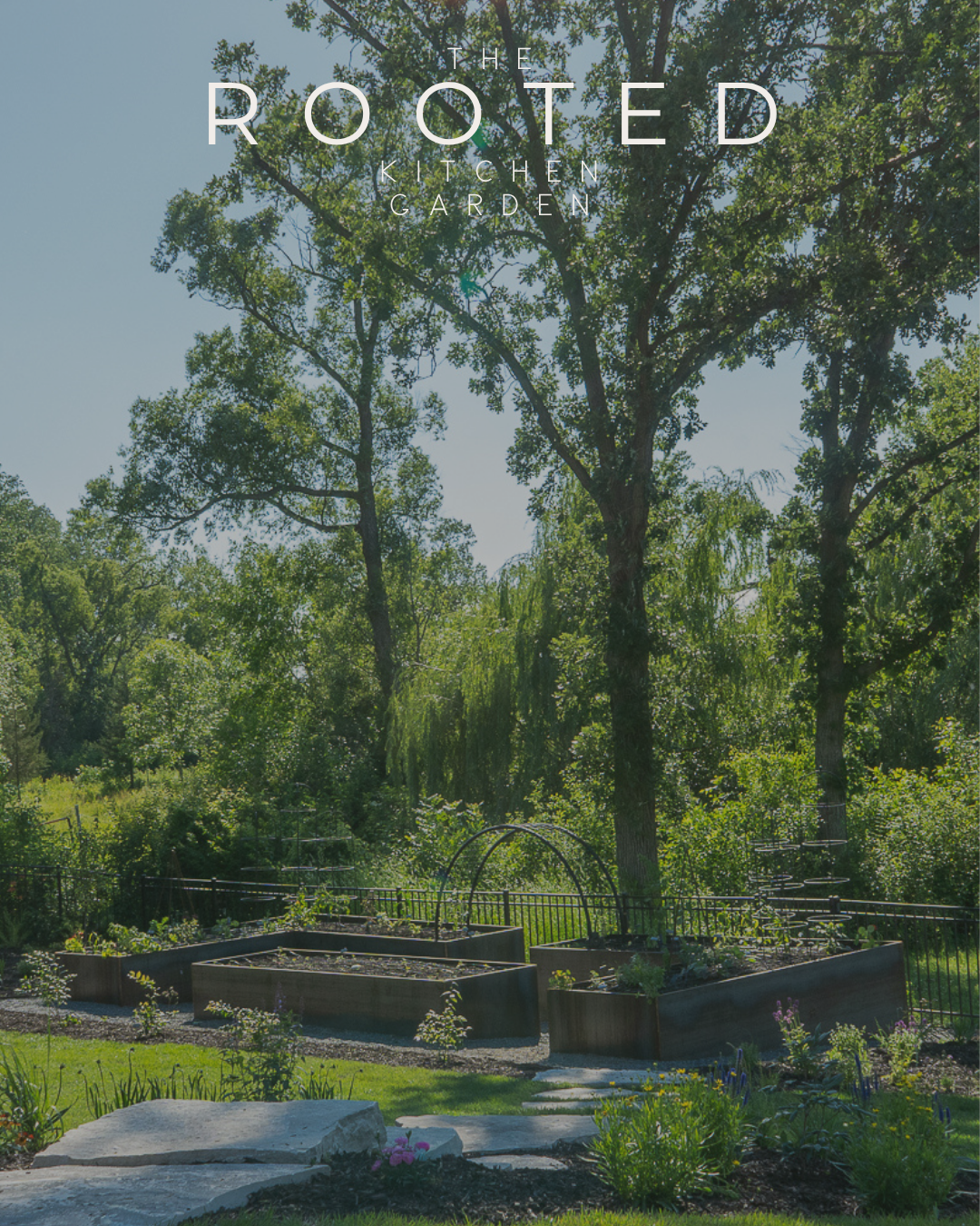 The Rooted Kitchen Garden with corten steel raised beds and custom black trellises, surrounded by mature trees and lush landscaping.