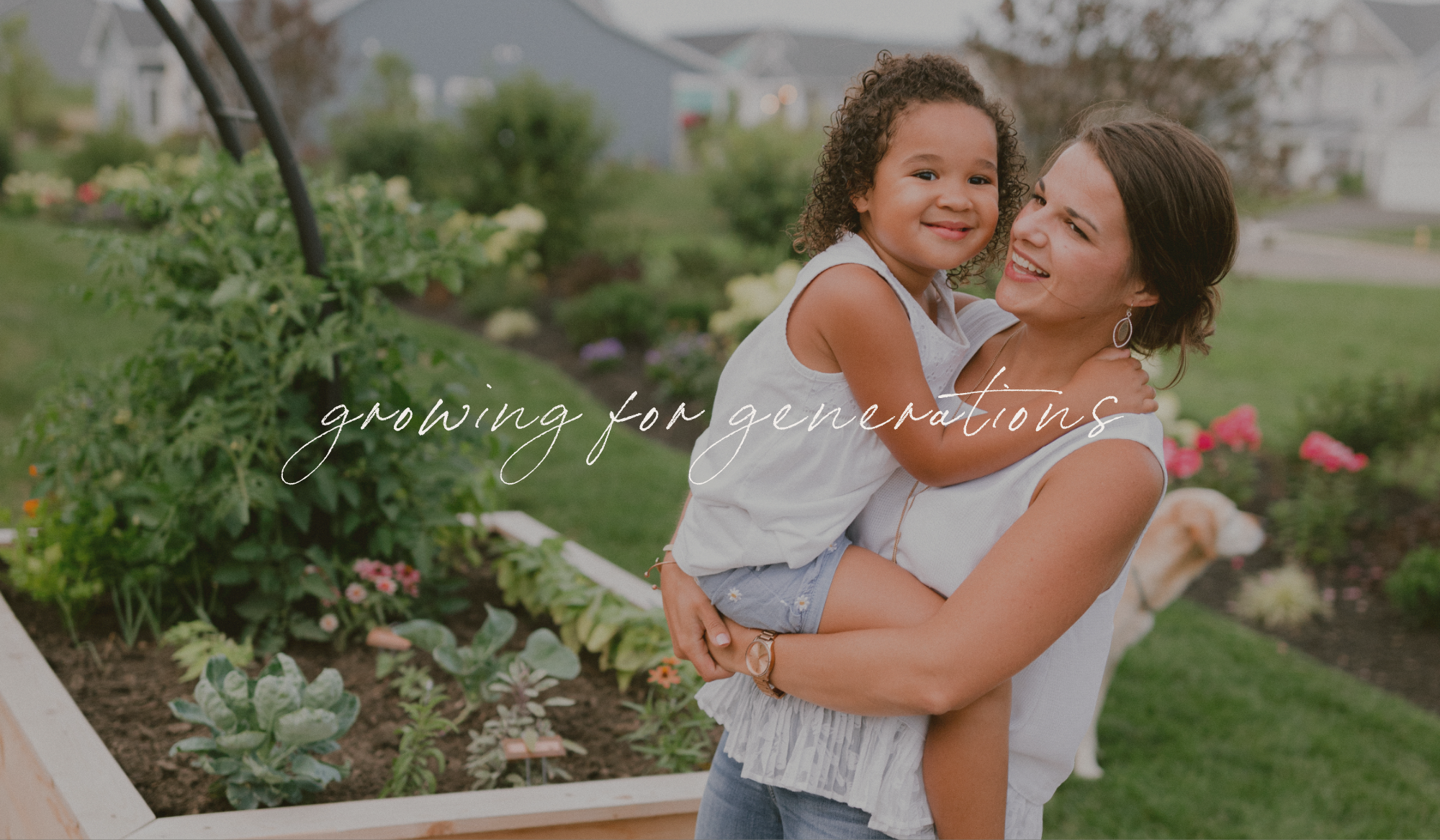 A mother holding her young daughter beside the family kitchen garden with the words “growing for generations.”
