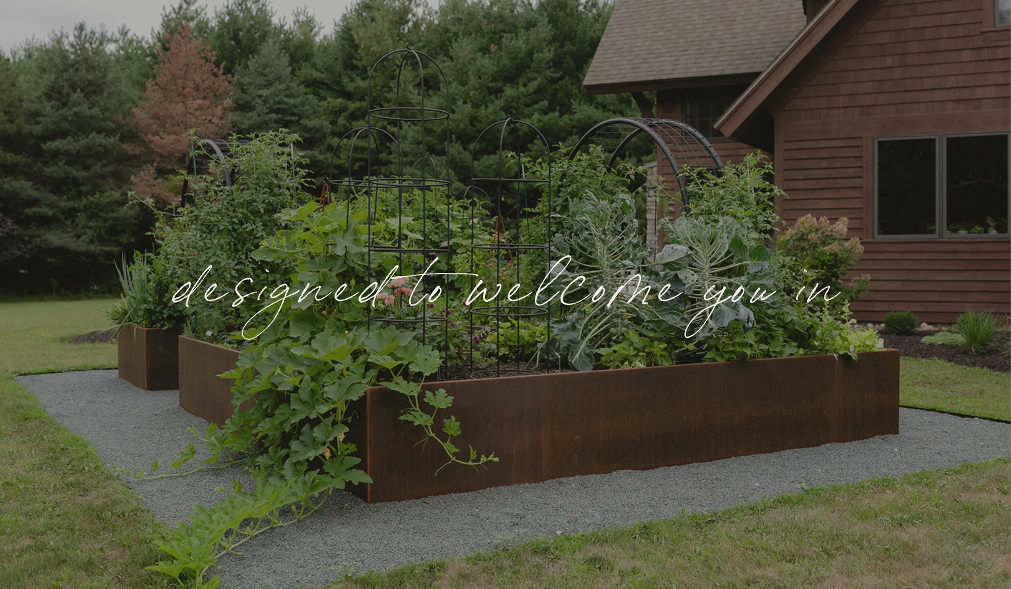 The Archway Garden with corten steel raised beds and black arch trellises, designed as a welcoming entrance into the kitchen garden.