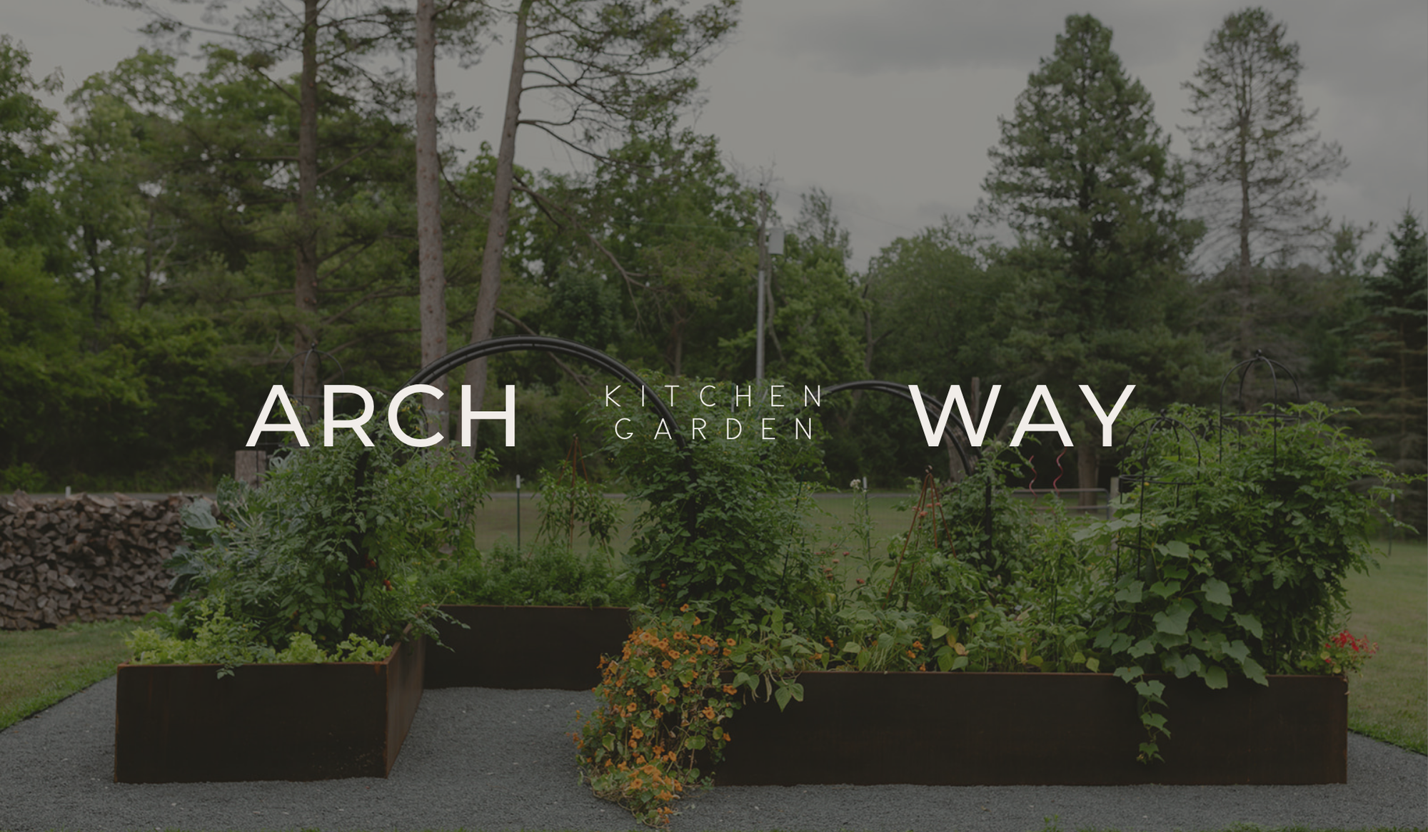 The Archway Garden featuring two corten steel raised beds, black arch trellises, and a lush kitchen garden in Fontana, Wisconsin.”