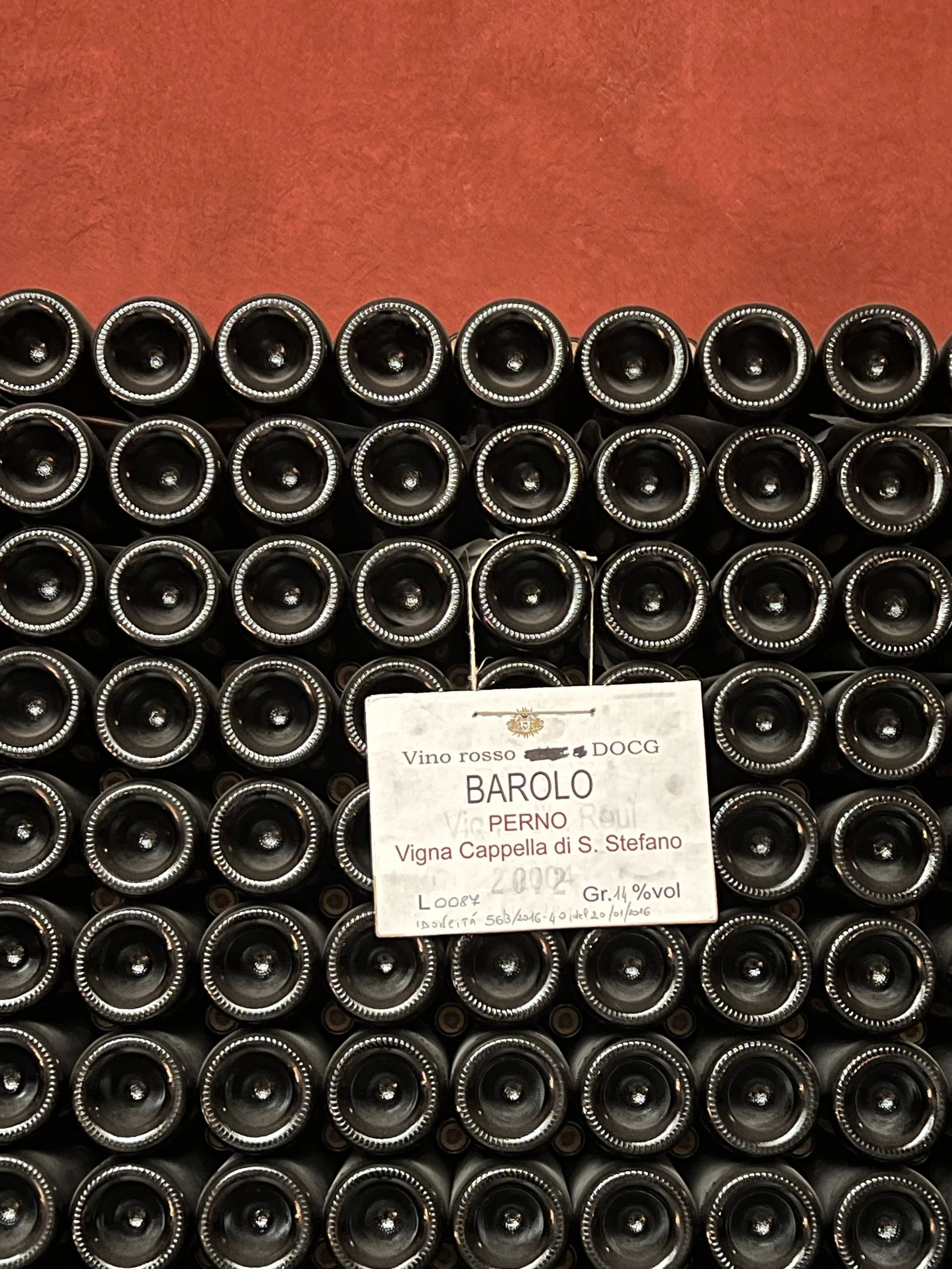 Stack of wine bottles with a label reading BAROLO, Perno, Vigna Cappella di S. Stefano, 2002, 14% alcohol.