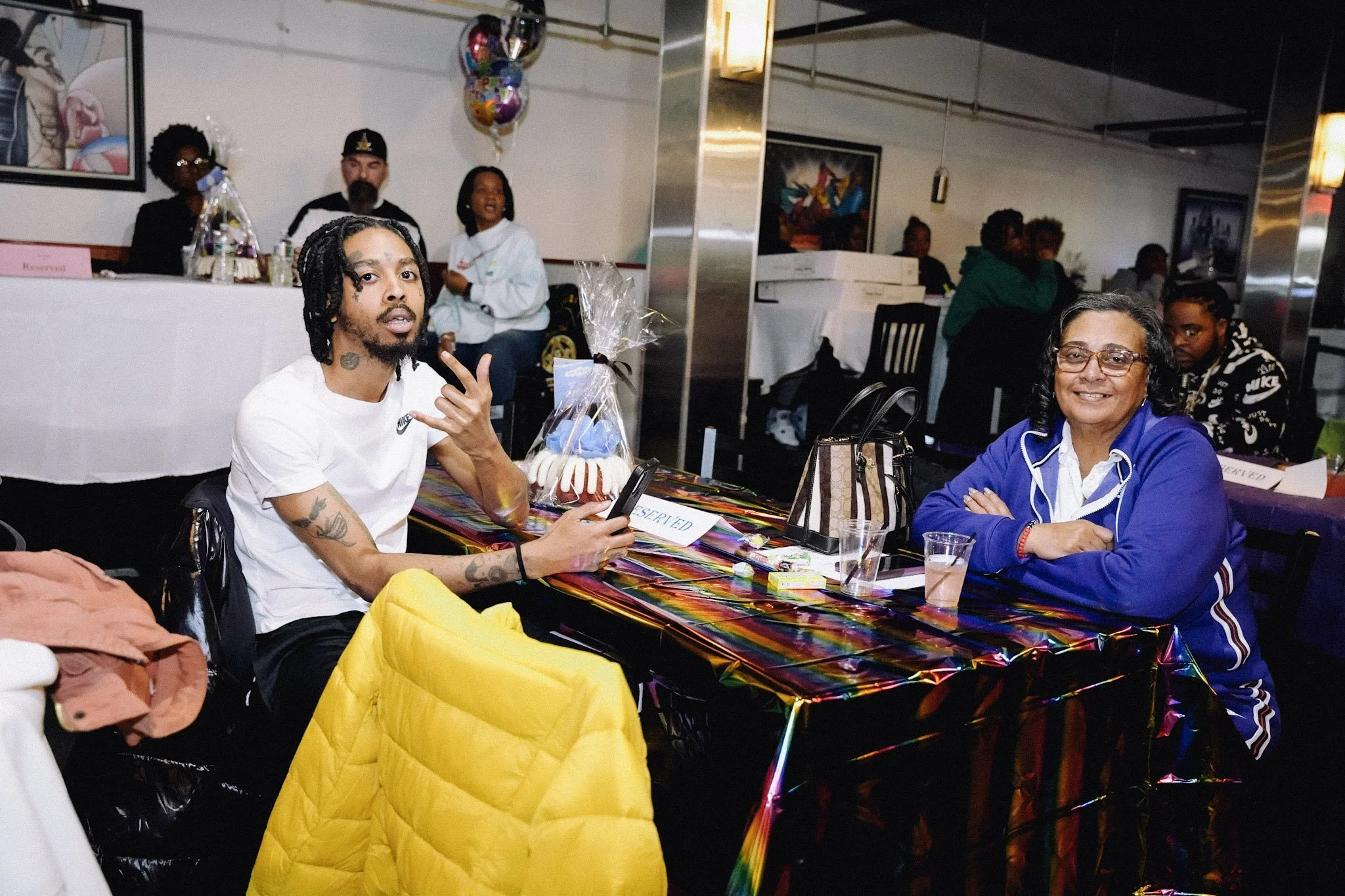 A group of people sitting at a colorful table during a celebration at a restaurant.