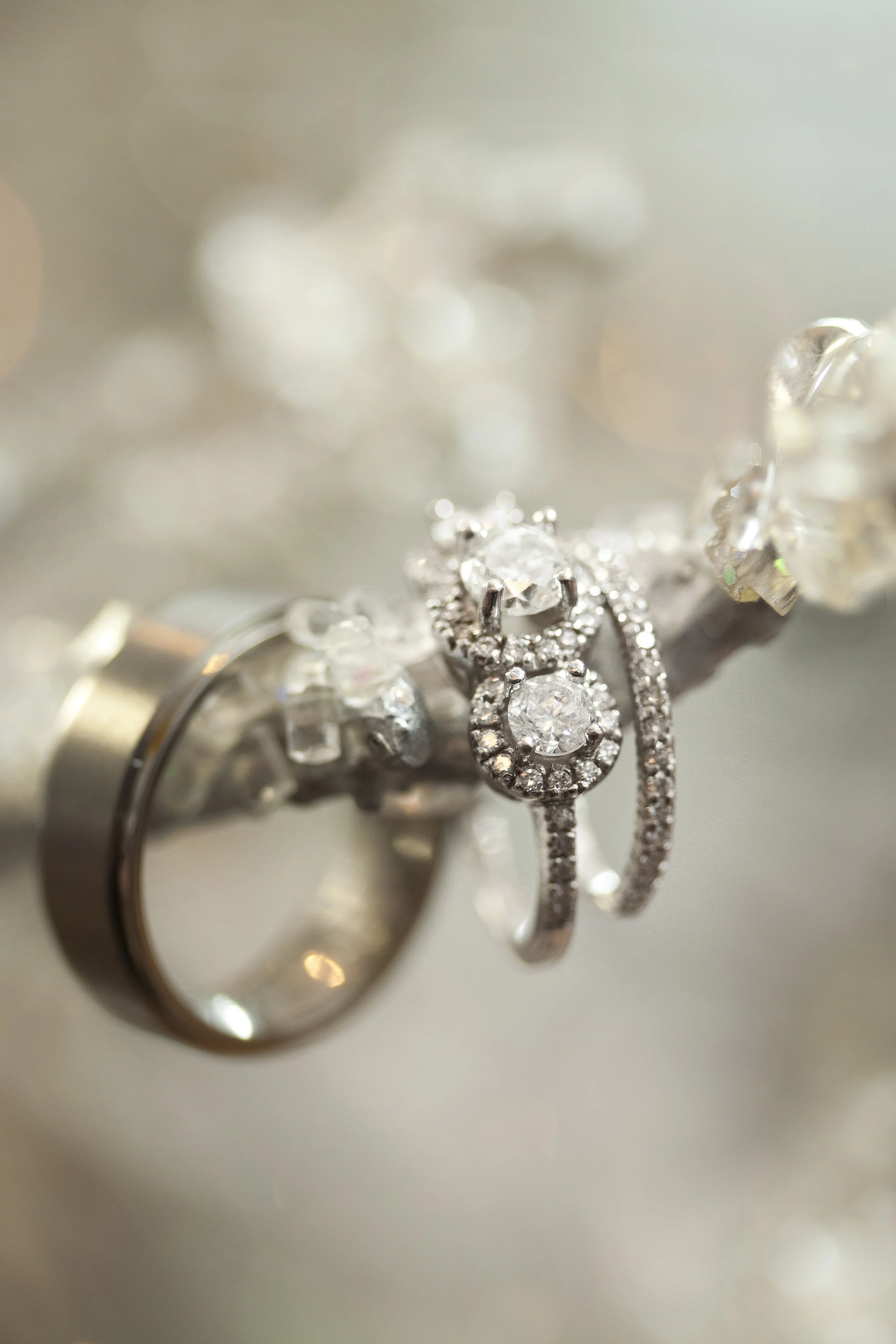 Close-up of diamond wedding rings and jewelry on a silver branch.