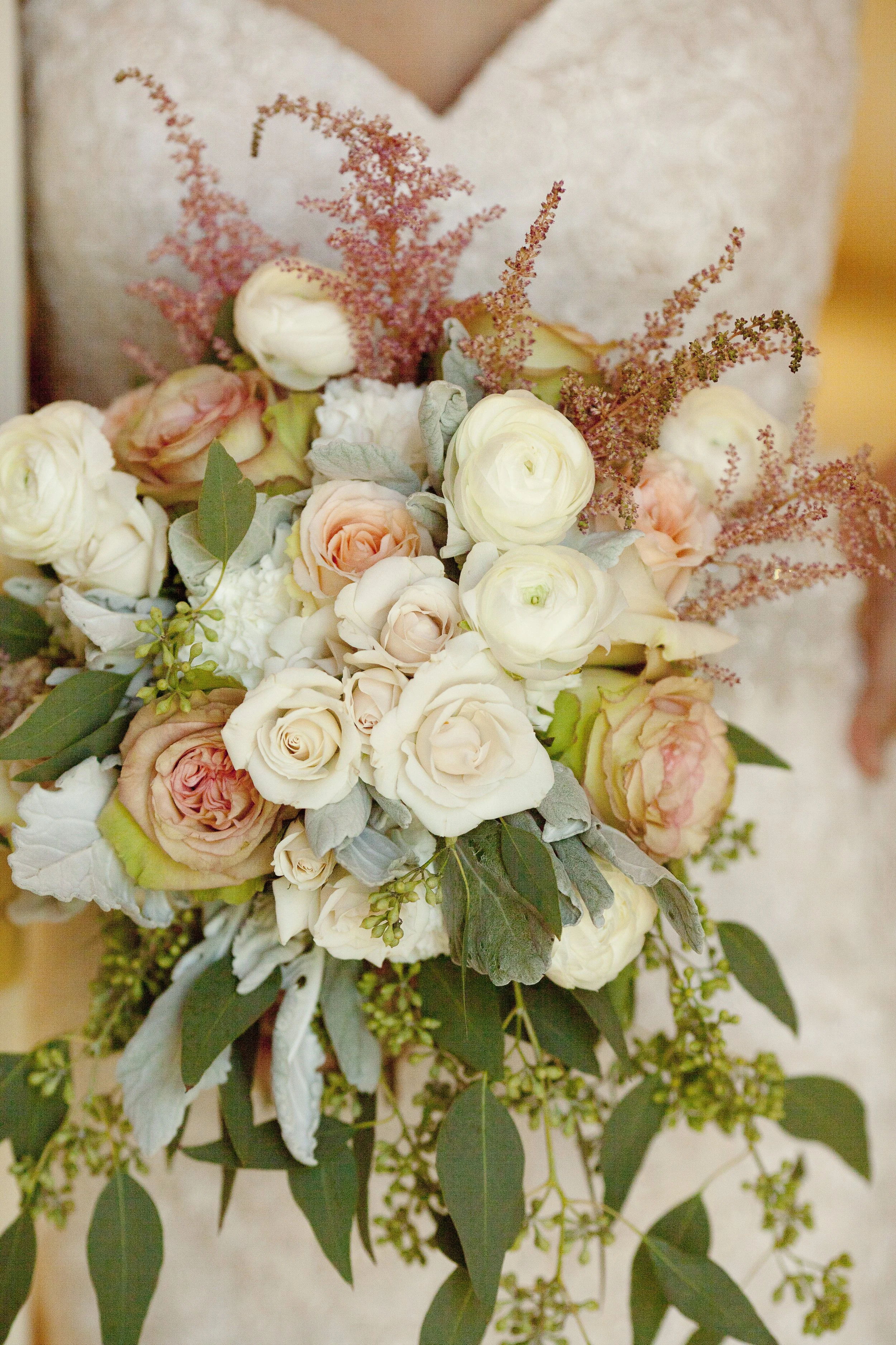 A bridal bouquet with white and peach roses, pink astilbe, and green foliage.