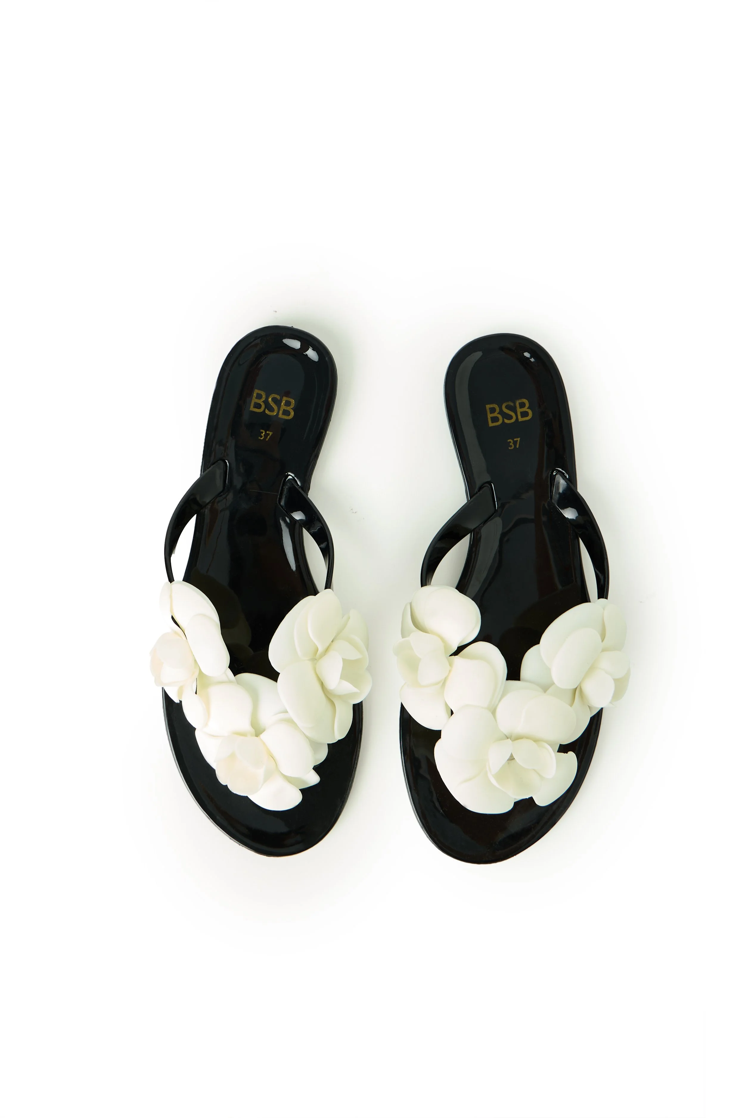 Pair of black sandals decorated with white flowers, placed on a white background.