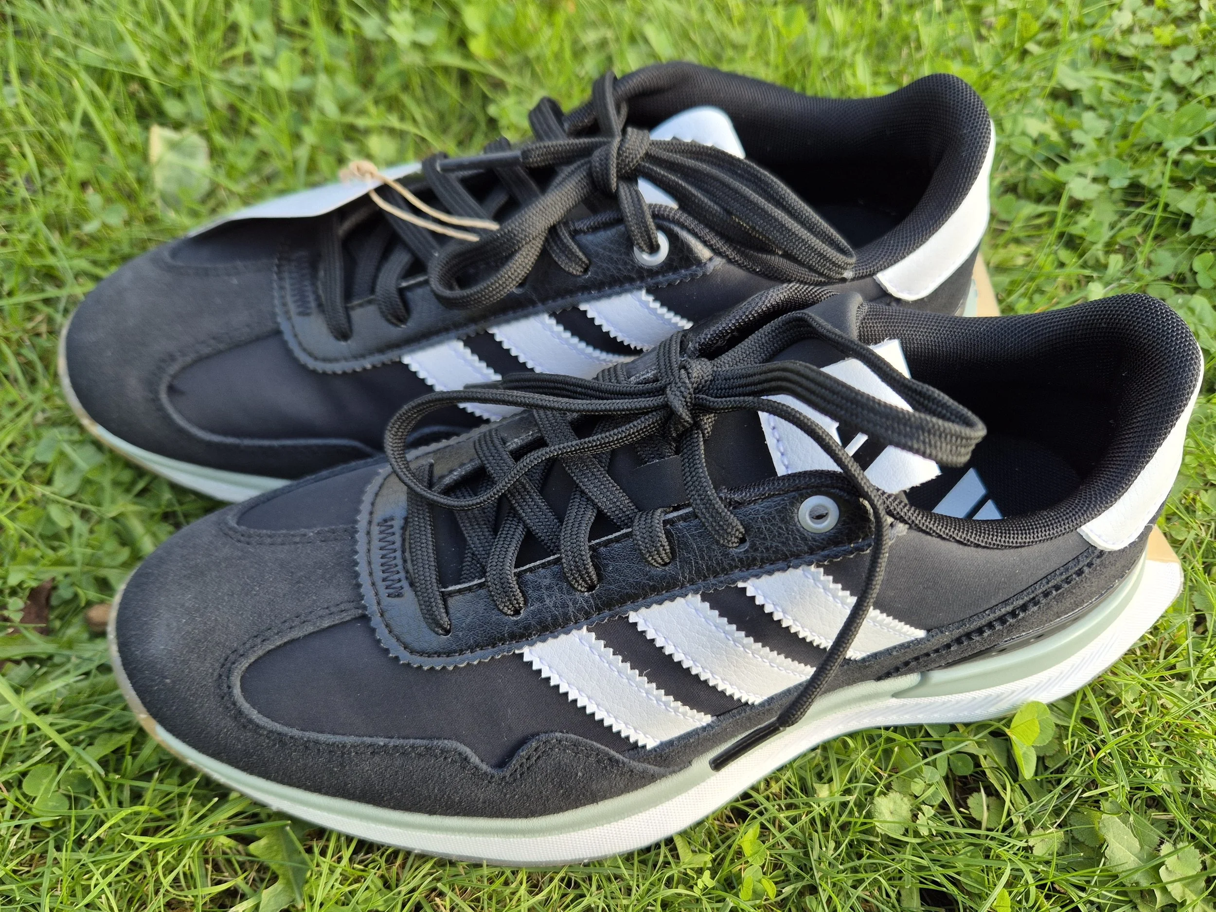 Black Adidas lace-up spikeless golf shoes viewed from the front.
