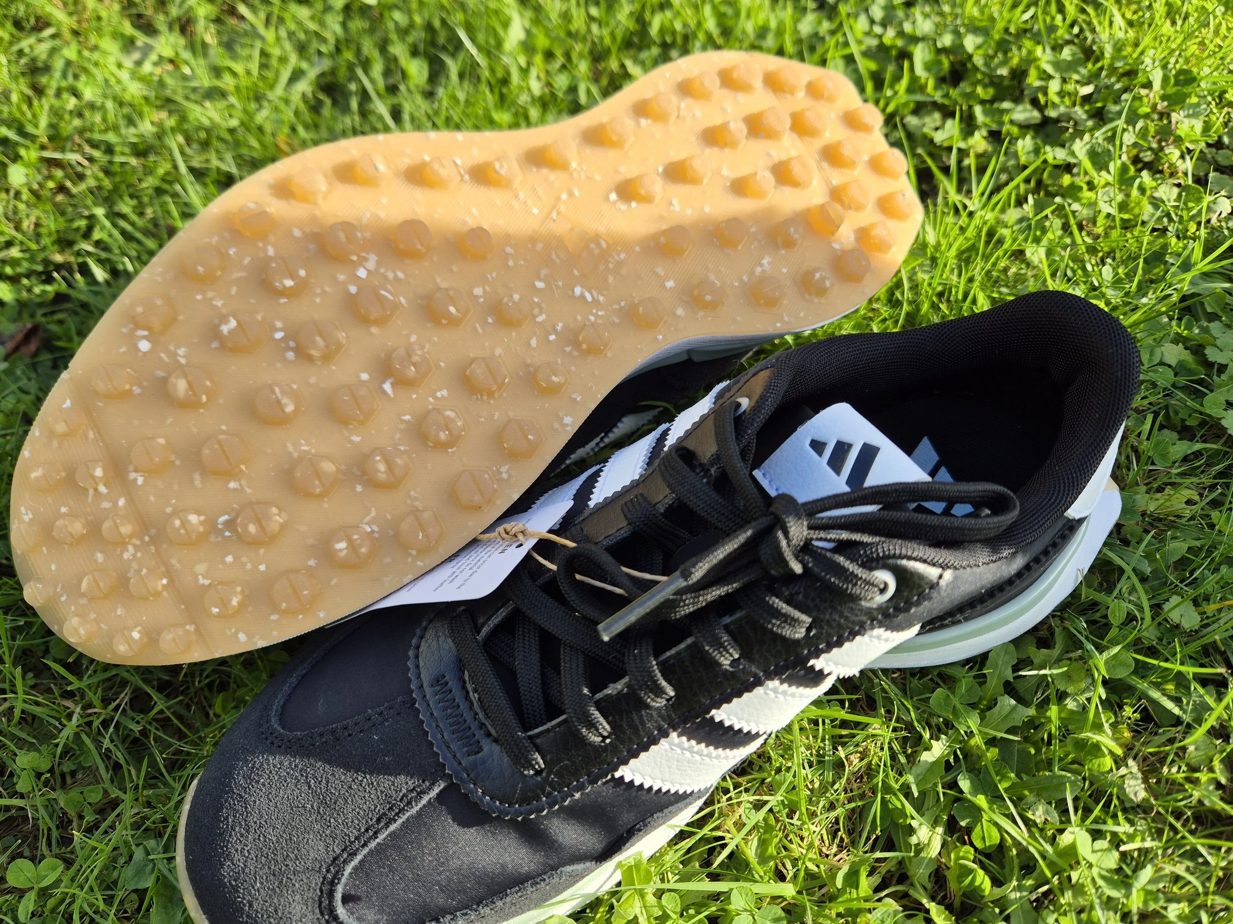 Adidas golf shoe sole showing spikeless traction pattern on grass.